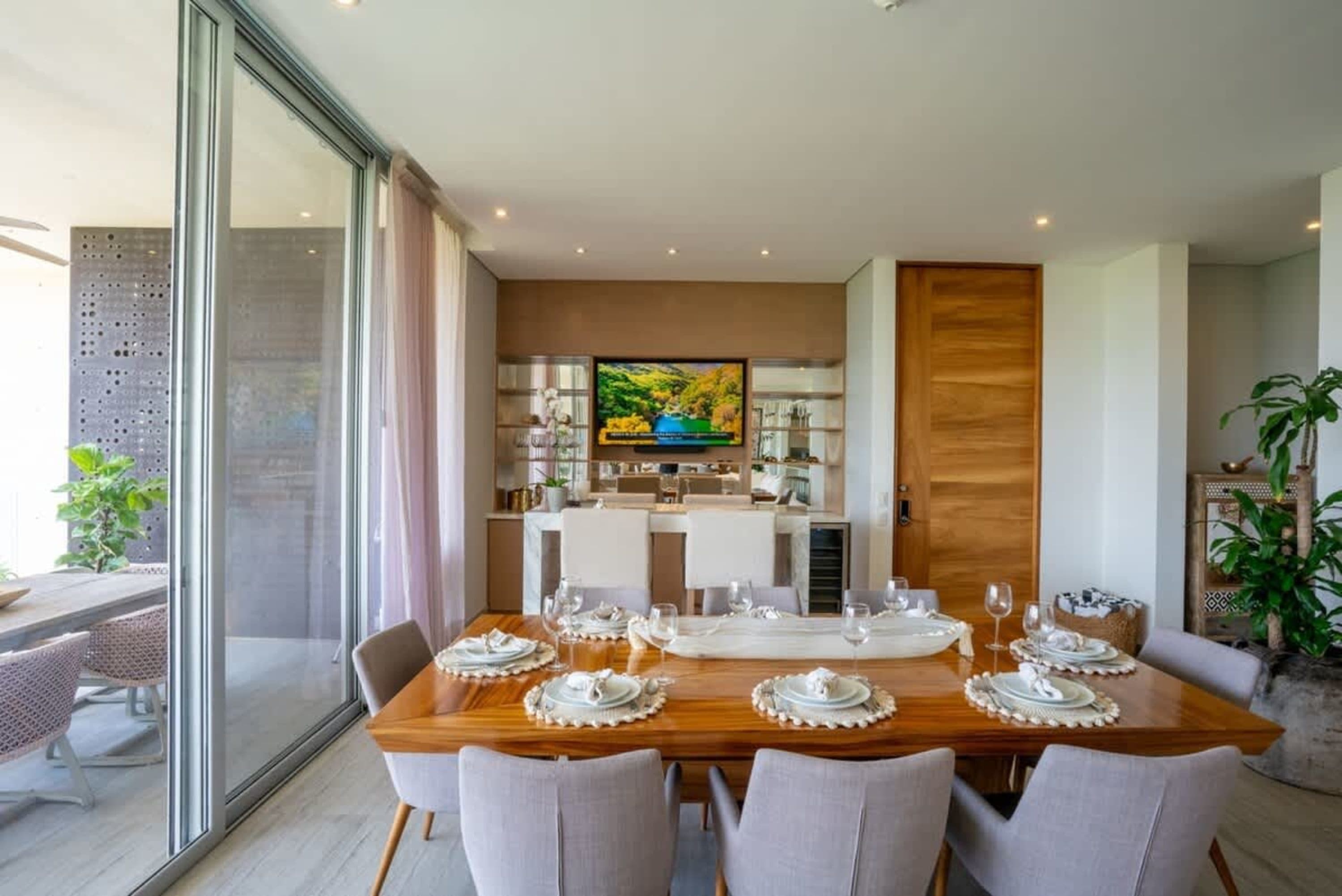 A stylish dining room with a large wooden table, chairs, and a bar area.