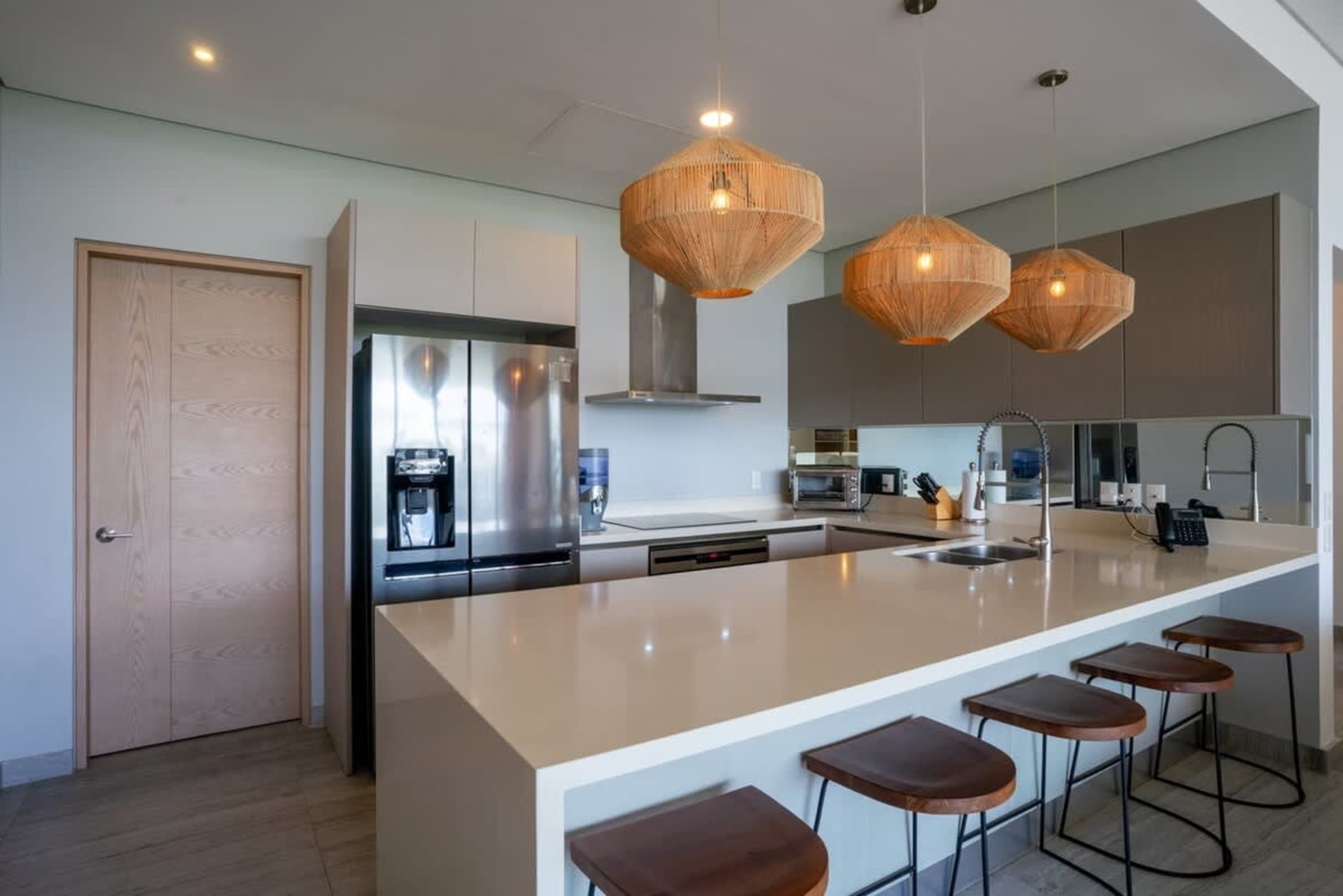 A modern kitchen with a large island, stainless steel appliances, and three pendant lights.
