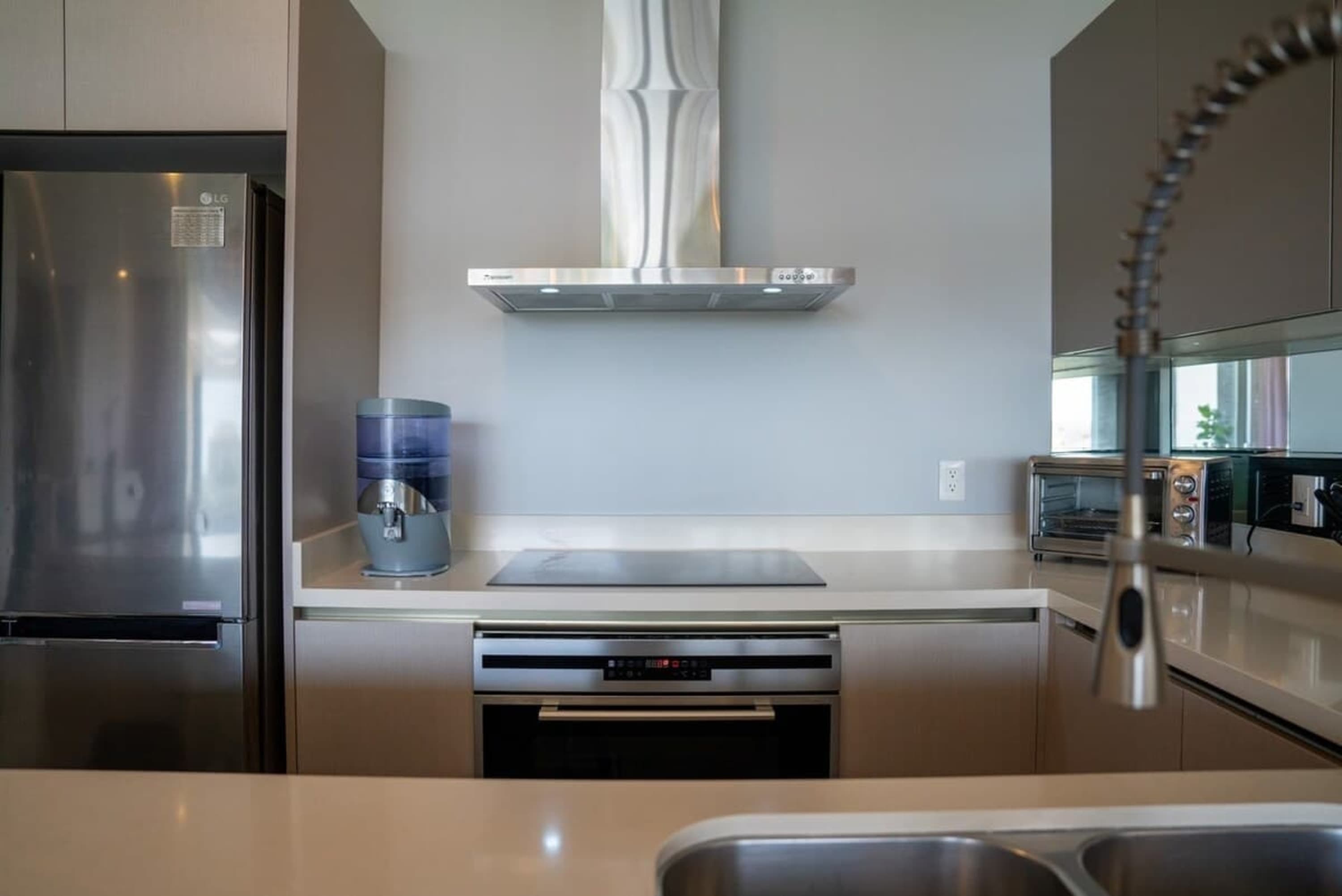 A modern kitchen features a stainless steel refrigerator, range hood, and built-in oven.