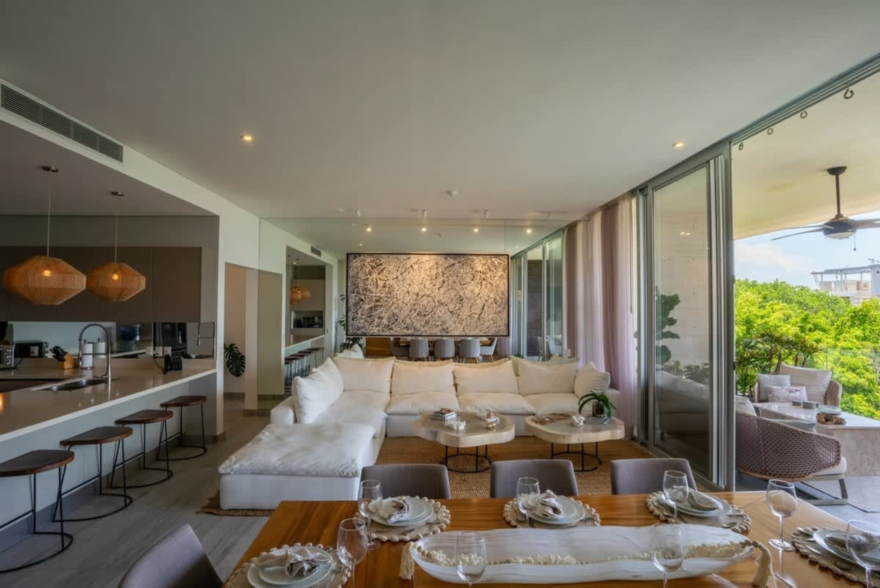 A modern living and dining room with a large sectional sofa, abstract art, and island bar.