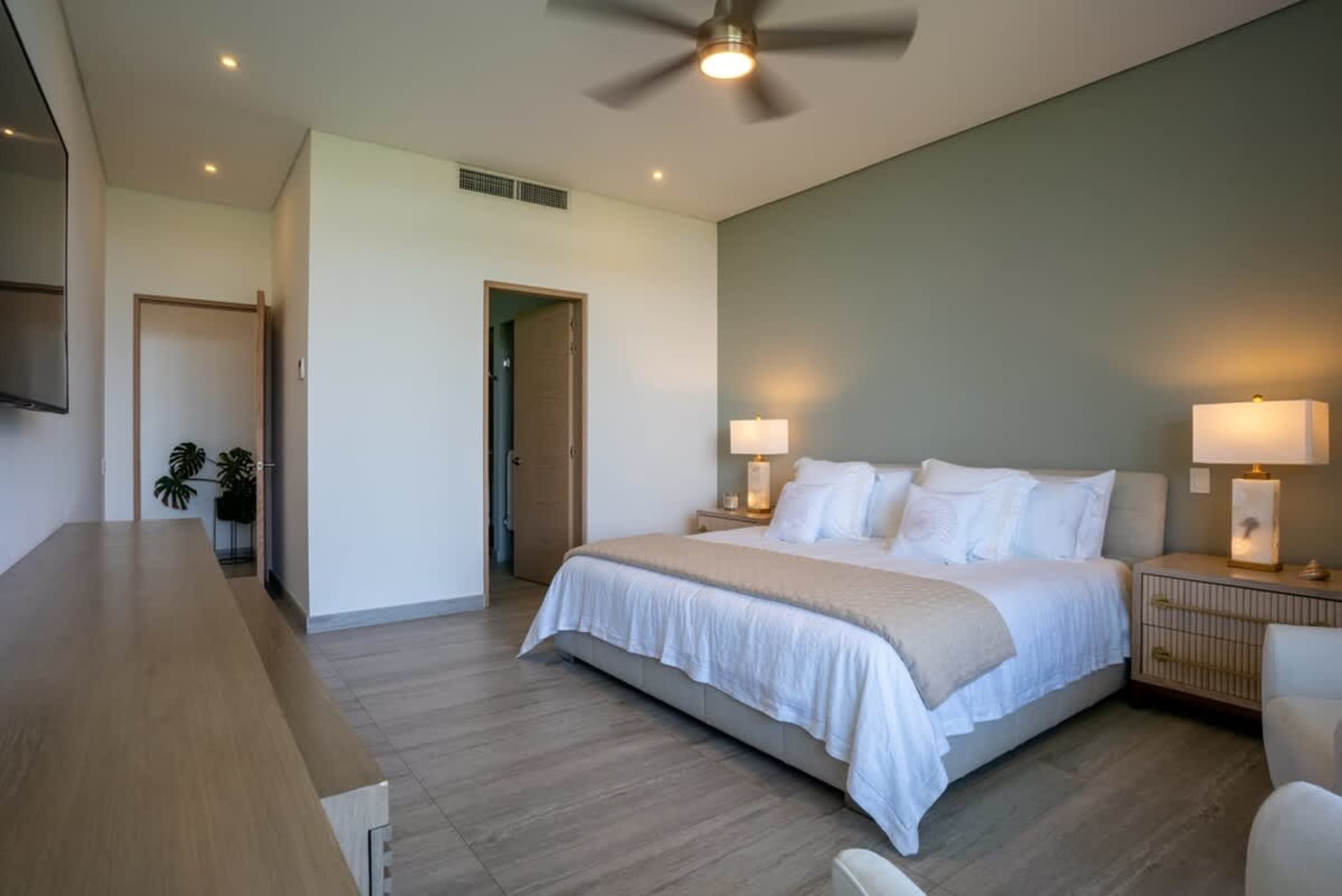 Modern bedroom with a large bed, bedside lamps, and a ceiling fan.
