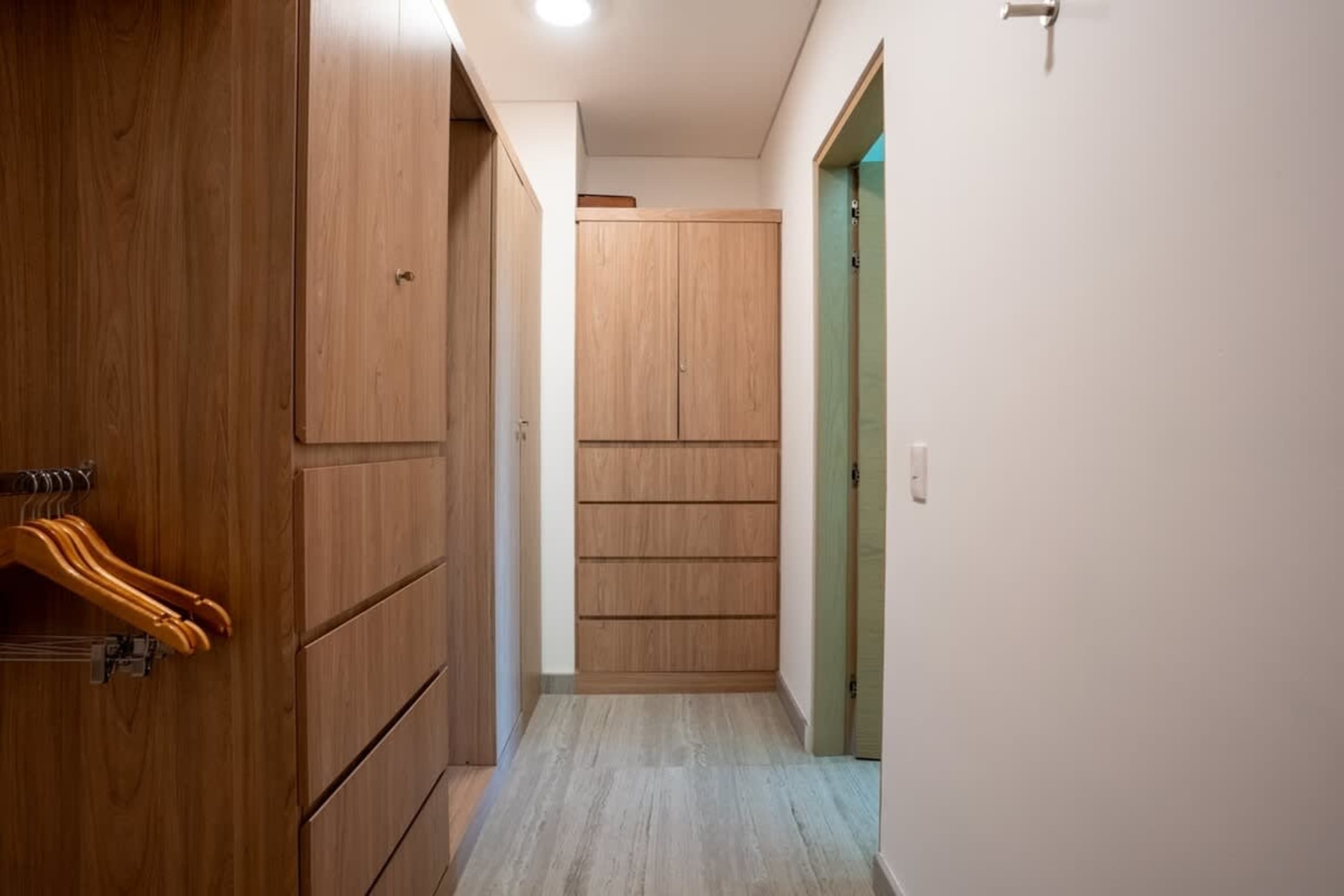 A wooden closet hallway with a door and a clothes hanger.