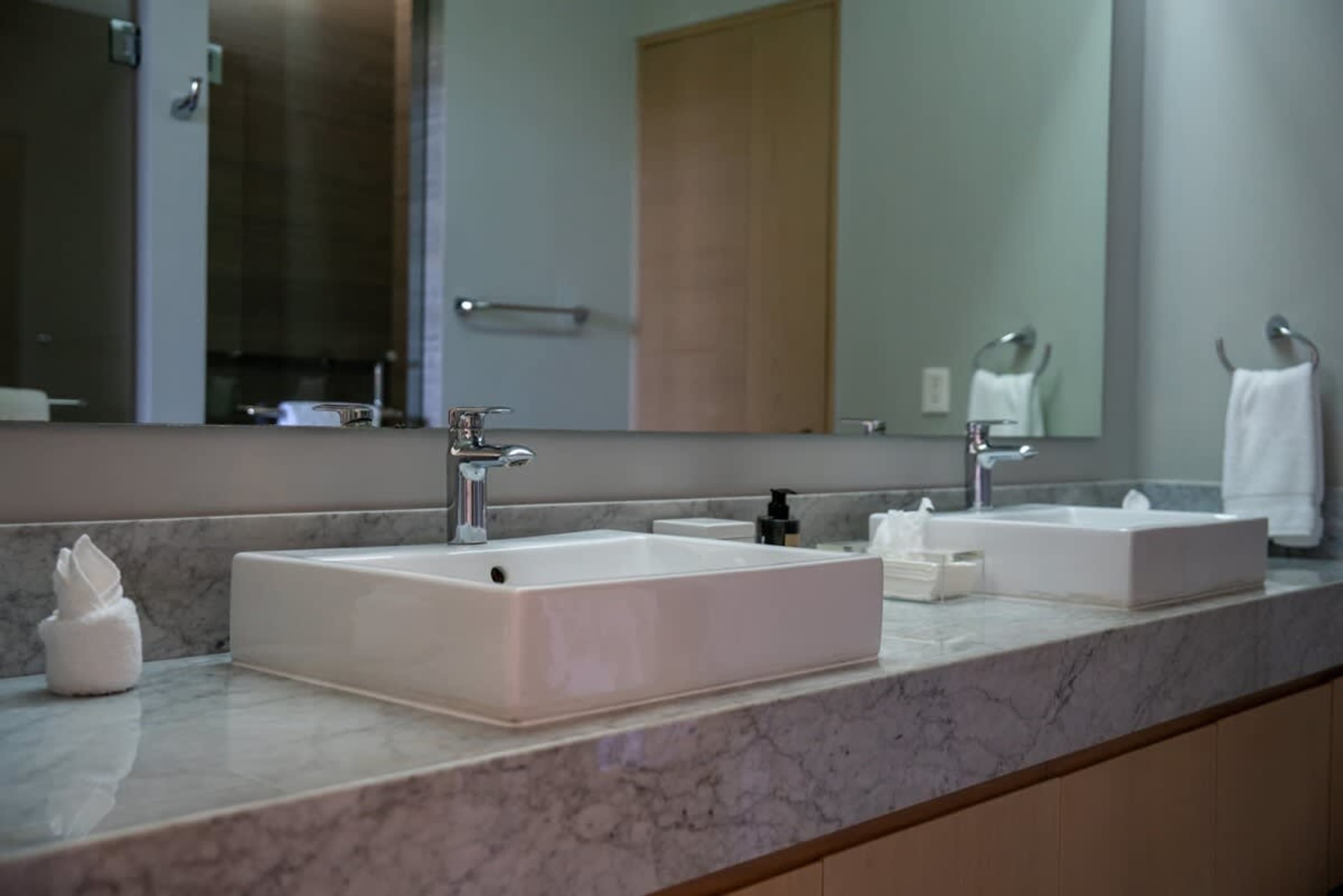 A modern bathroom vanity with two sinks and chrome faucets.