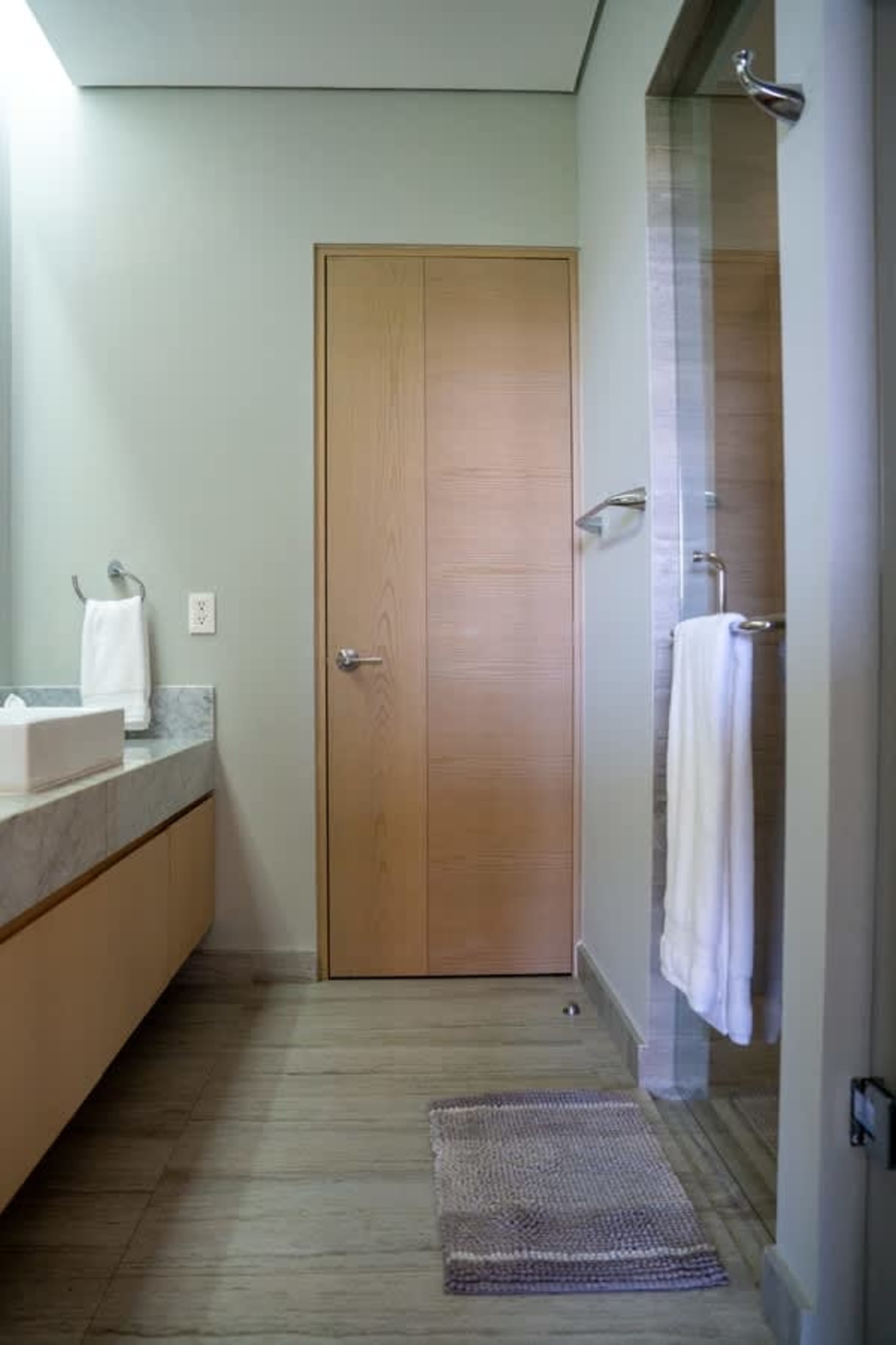 Bathroom with a modern aesthetic, featuring a double door, a vanity, and a glass shower.