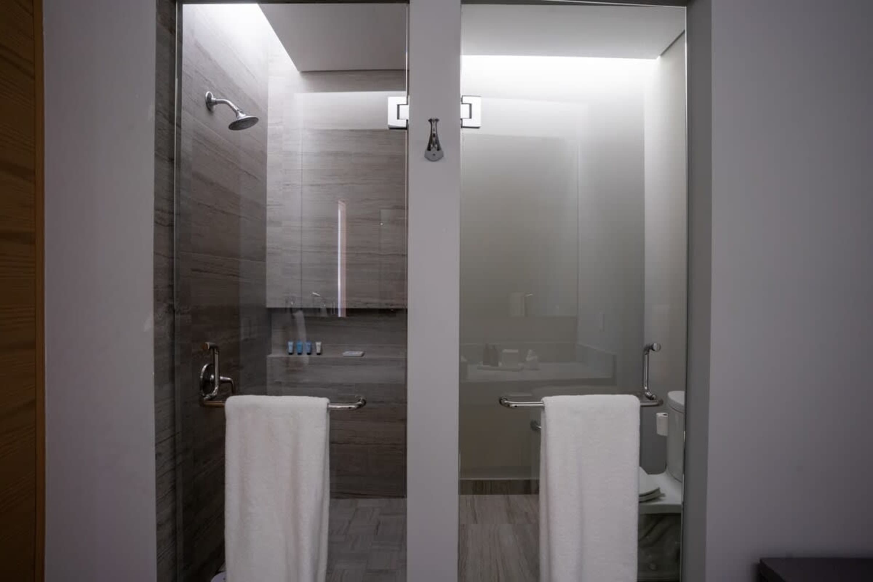 Modern bathroom with glass-enclosed showers and white towels.