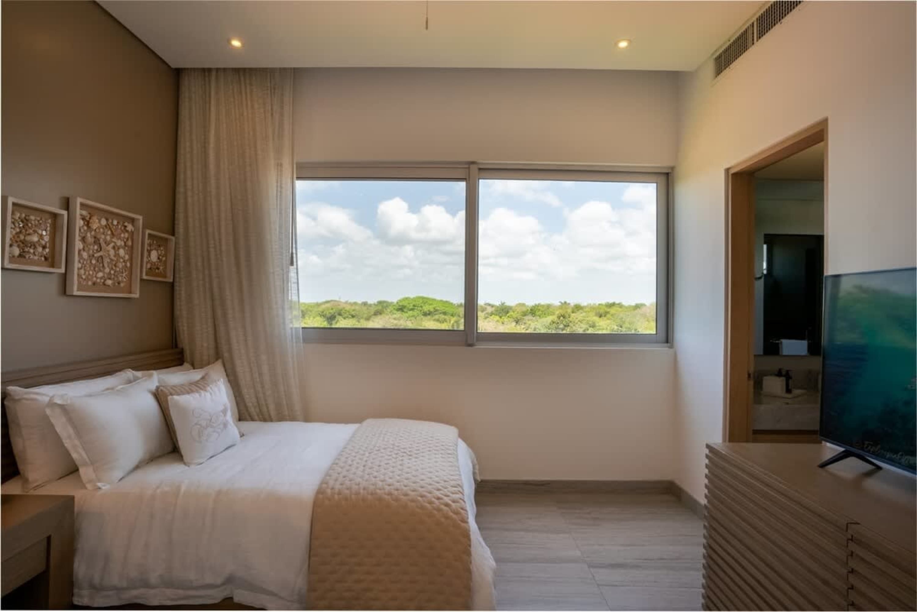 Bedroom with a bed, window with a view of trees, and a TV.