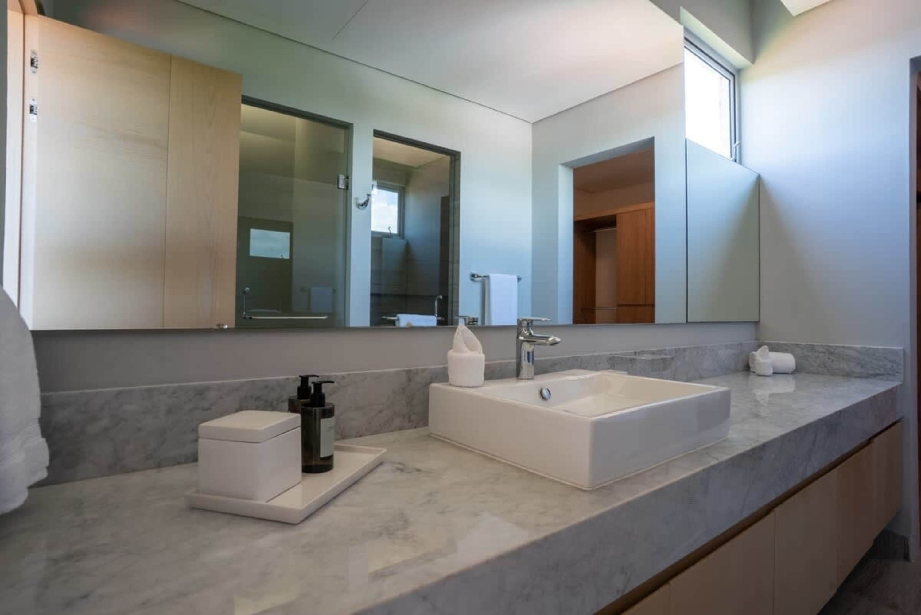 A modern bathroom vanity with a white sink and marble countertop.
