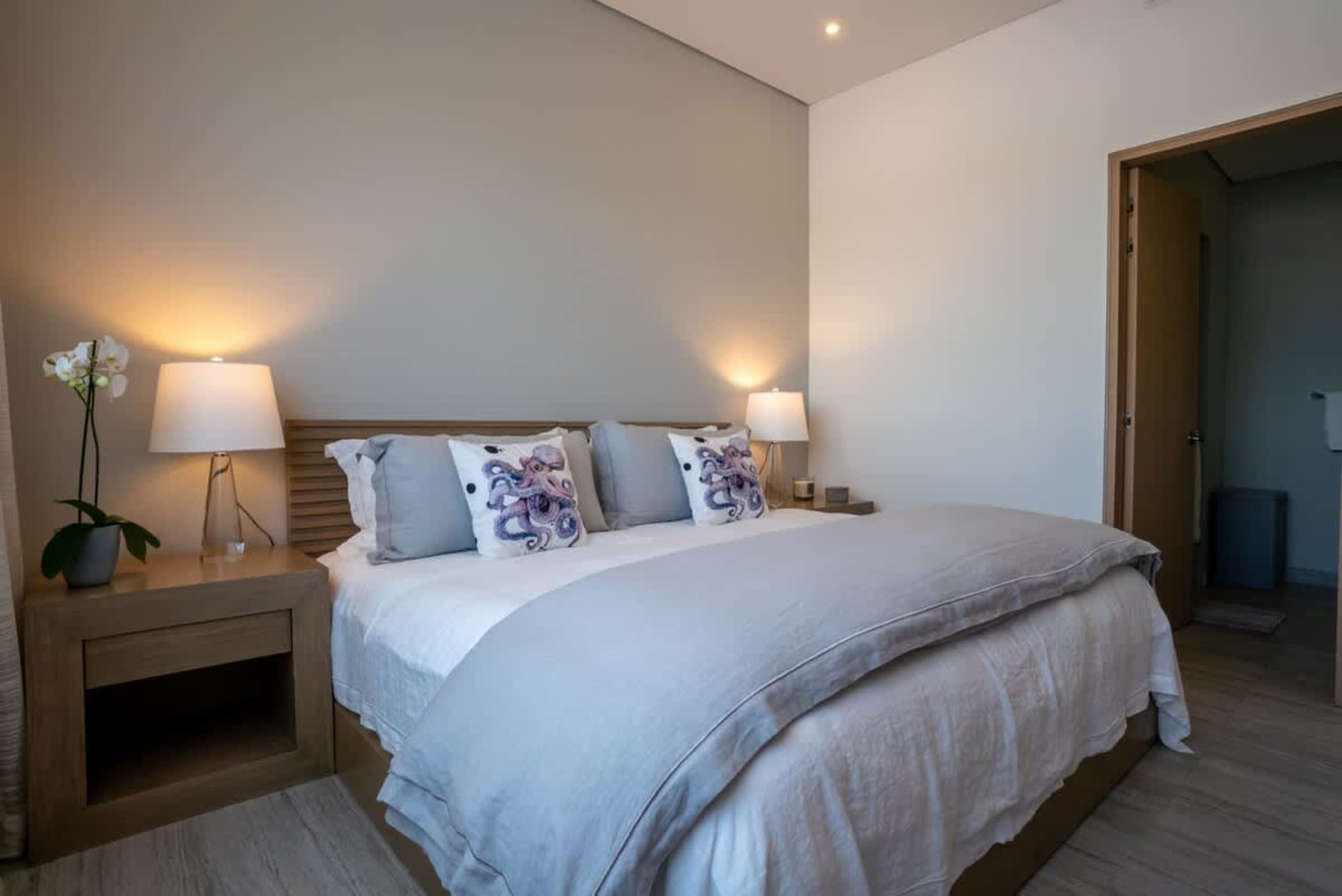 A bedroom with a large bed, nightstands, lamps, and decorative pillows.