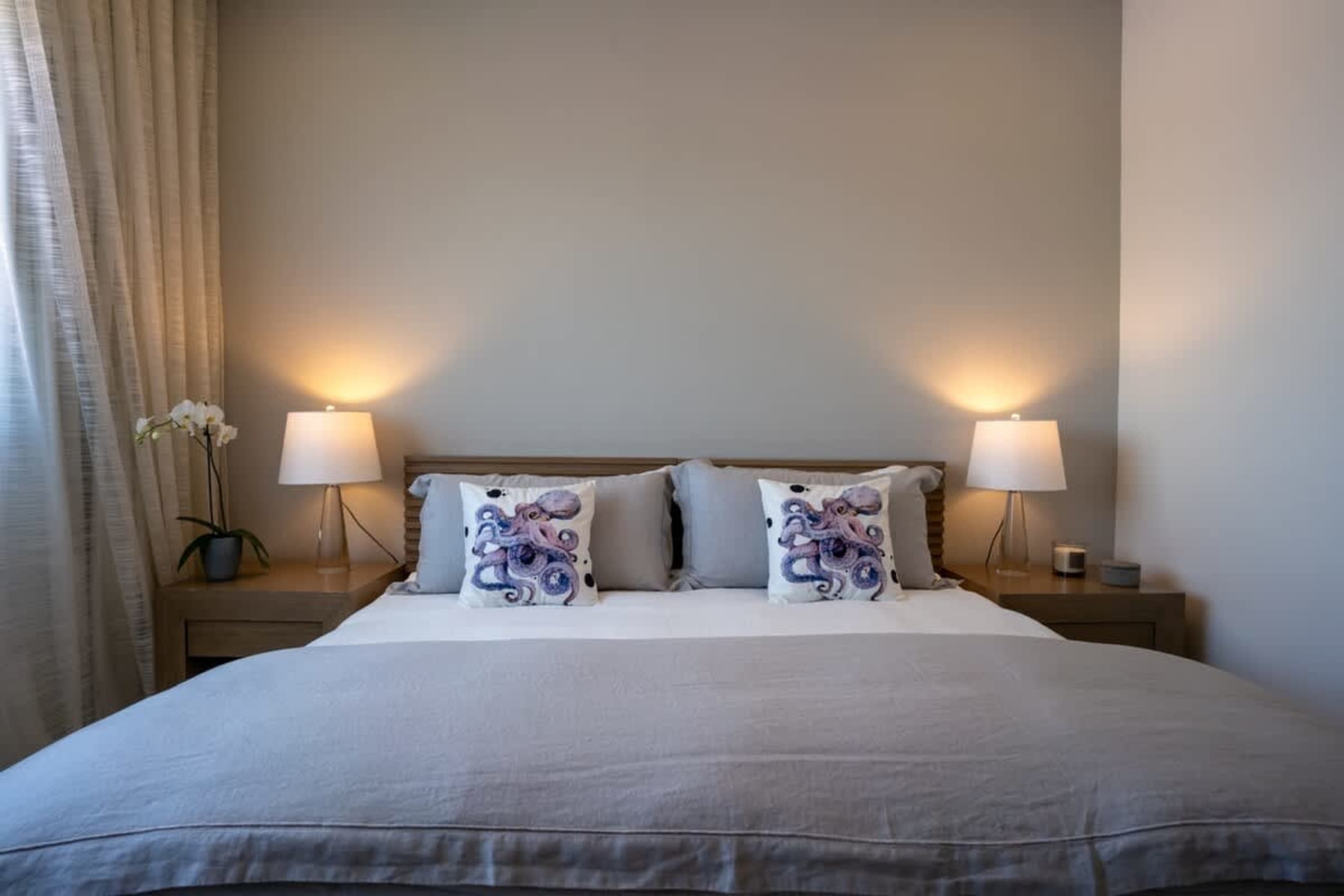 A cozy bedroom with a bed, two octopus pillows, and bedside lamps.