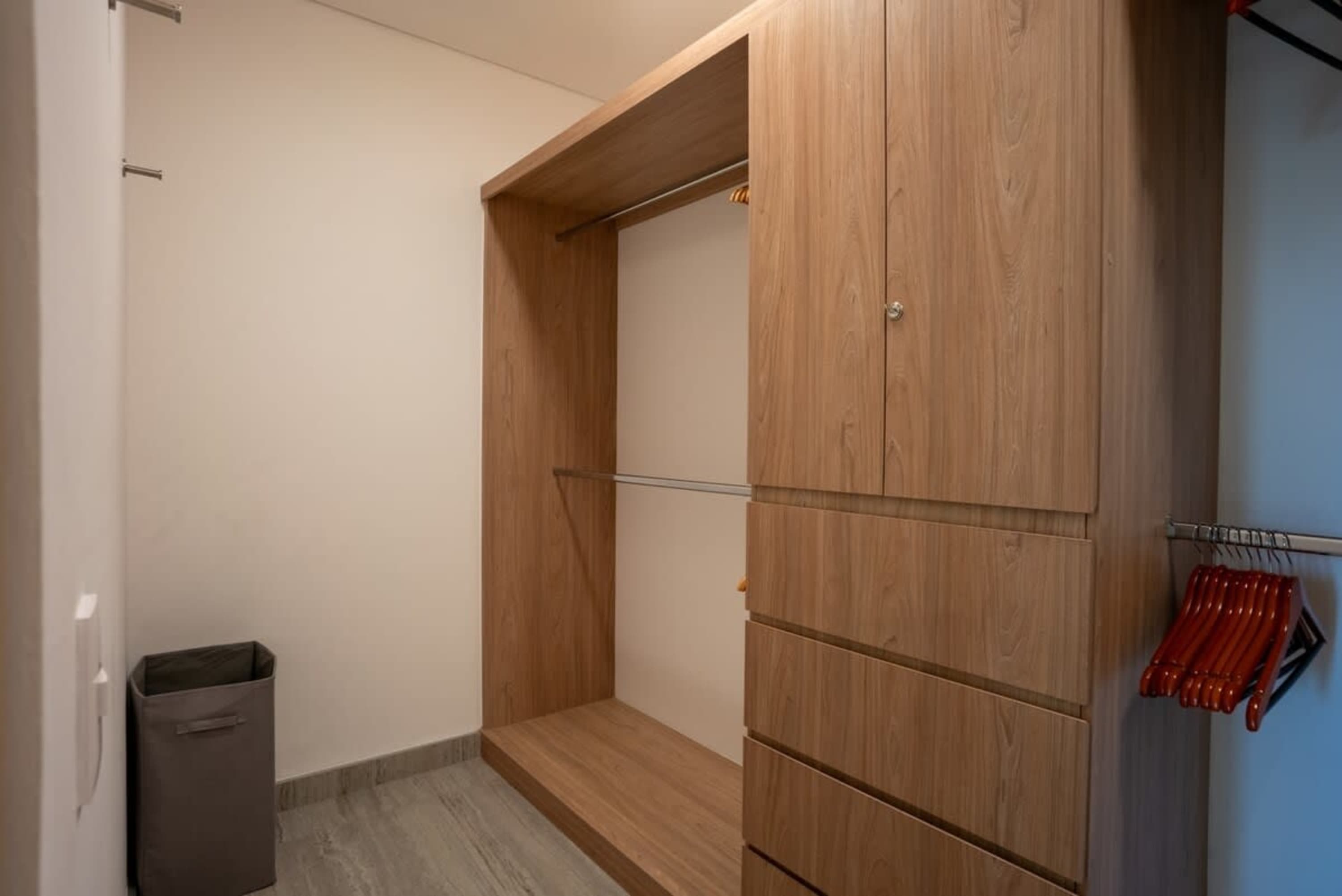 A wooden closet with drawers and a hanging rod.