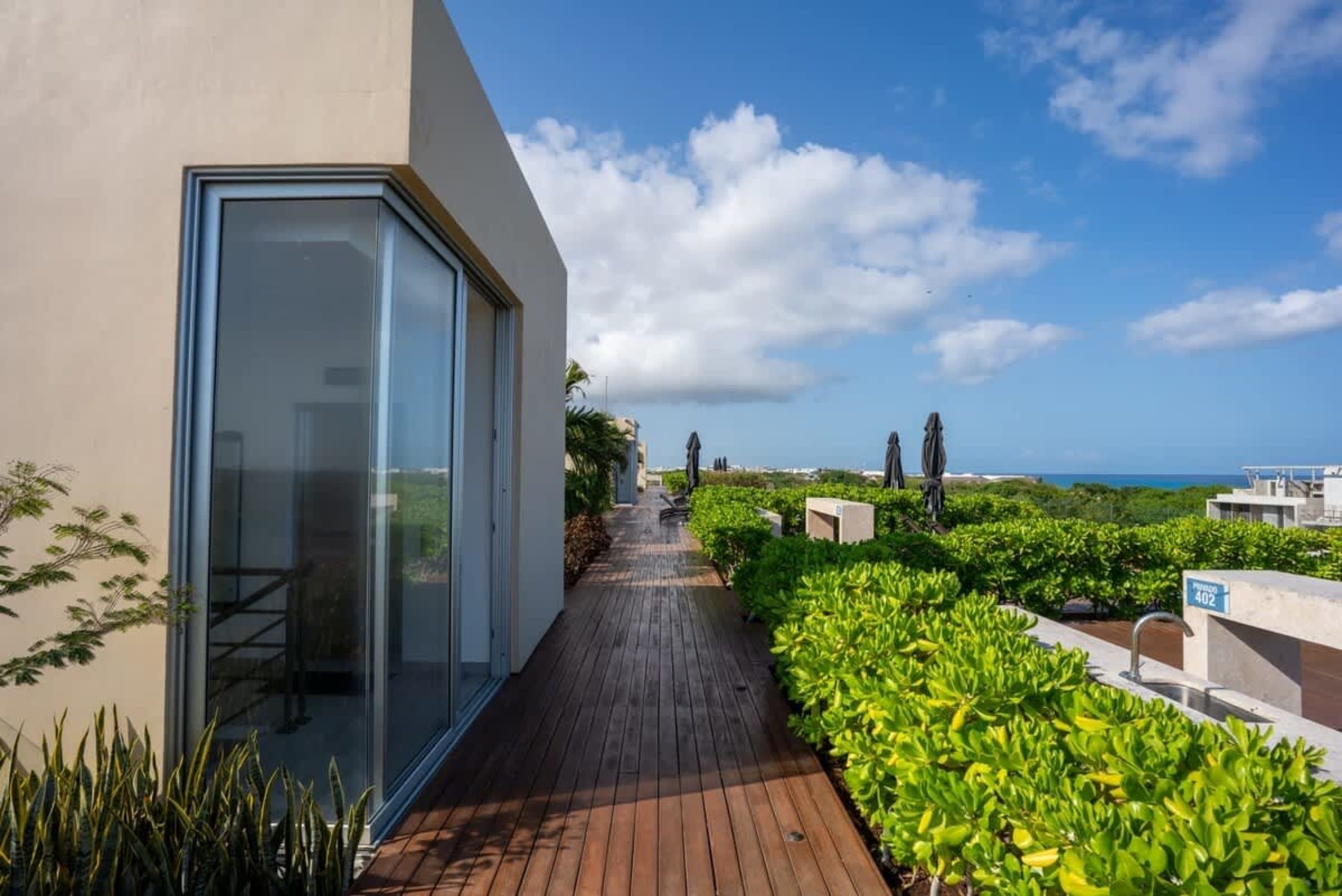 Rooftop deck with lounge chairs, umbrellas, and ocean views under a cloudy sky.