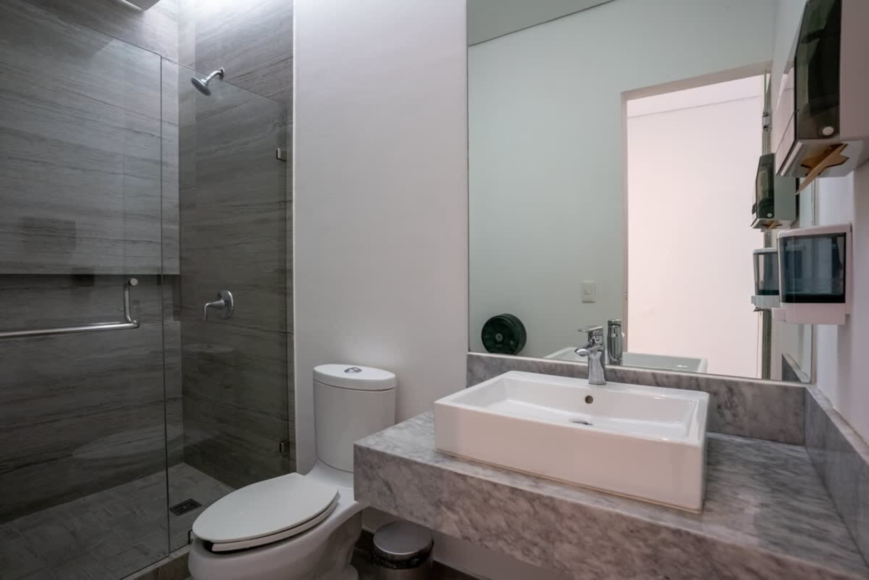 A modern bathroom with a walk-in shower, toilet, and sink with a marble countertop.