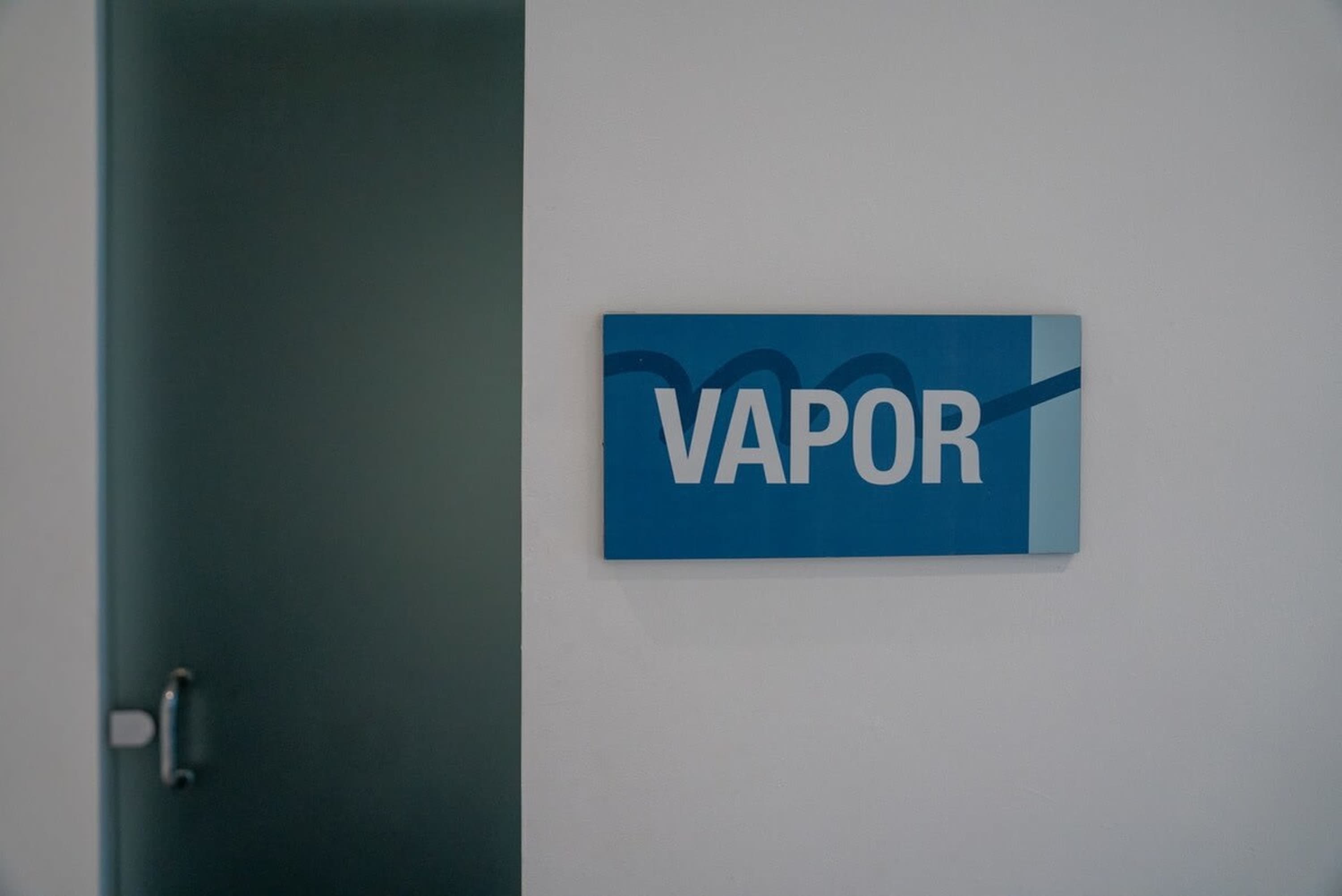 A blue sign with the word "VAPOR" in white text is mounted on a white wall.