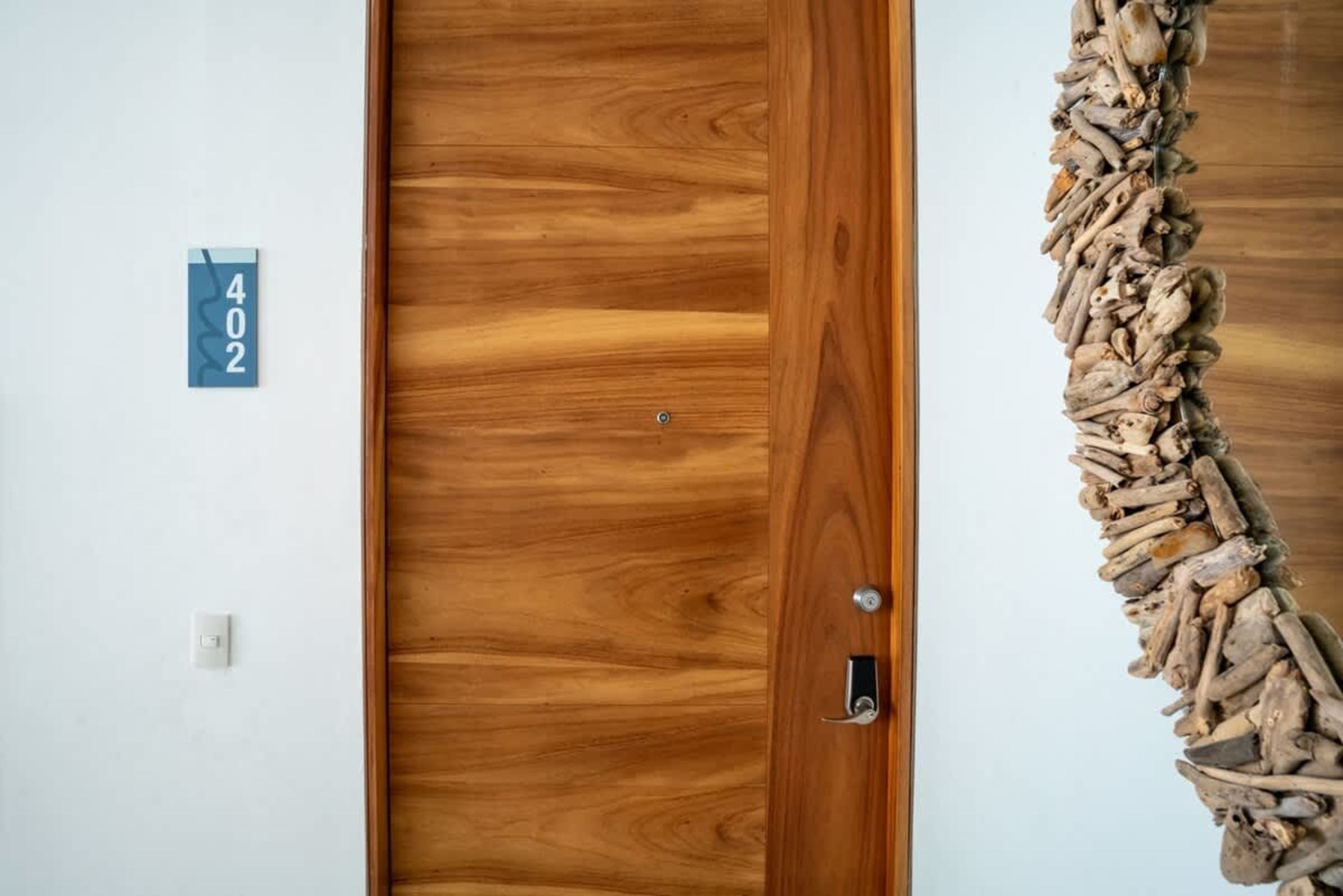 Door number 402 in a hotel room with a wooden door and a unique mirror.