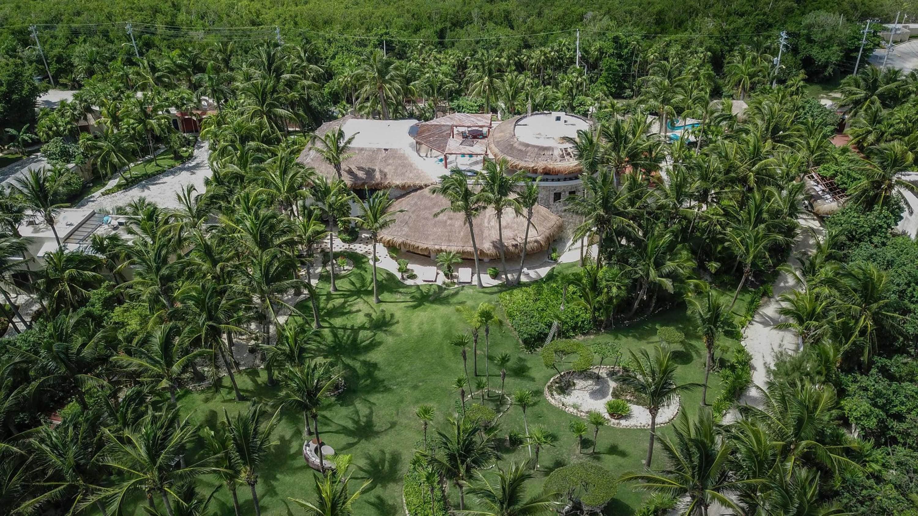 Aerial view of a circular resort surrounded by palm trees and lush greenery.