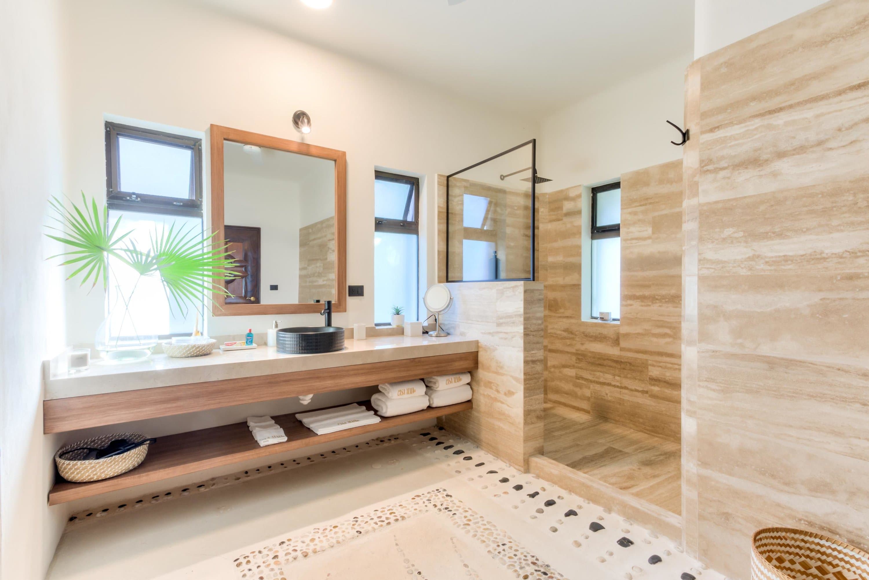 A modern bathroom with a black vessel sink and a glass-enclosed shower.