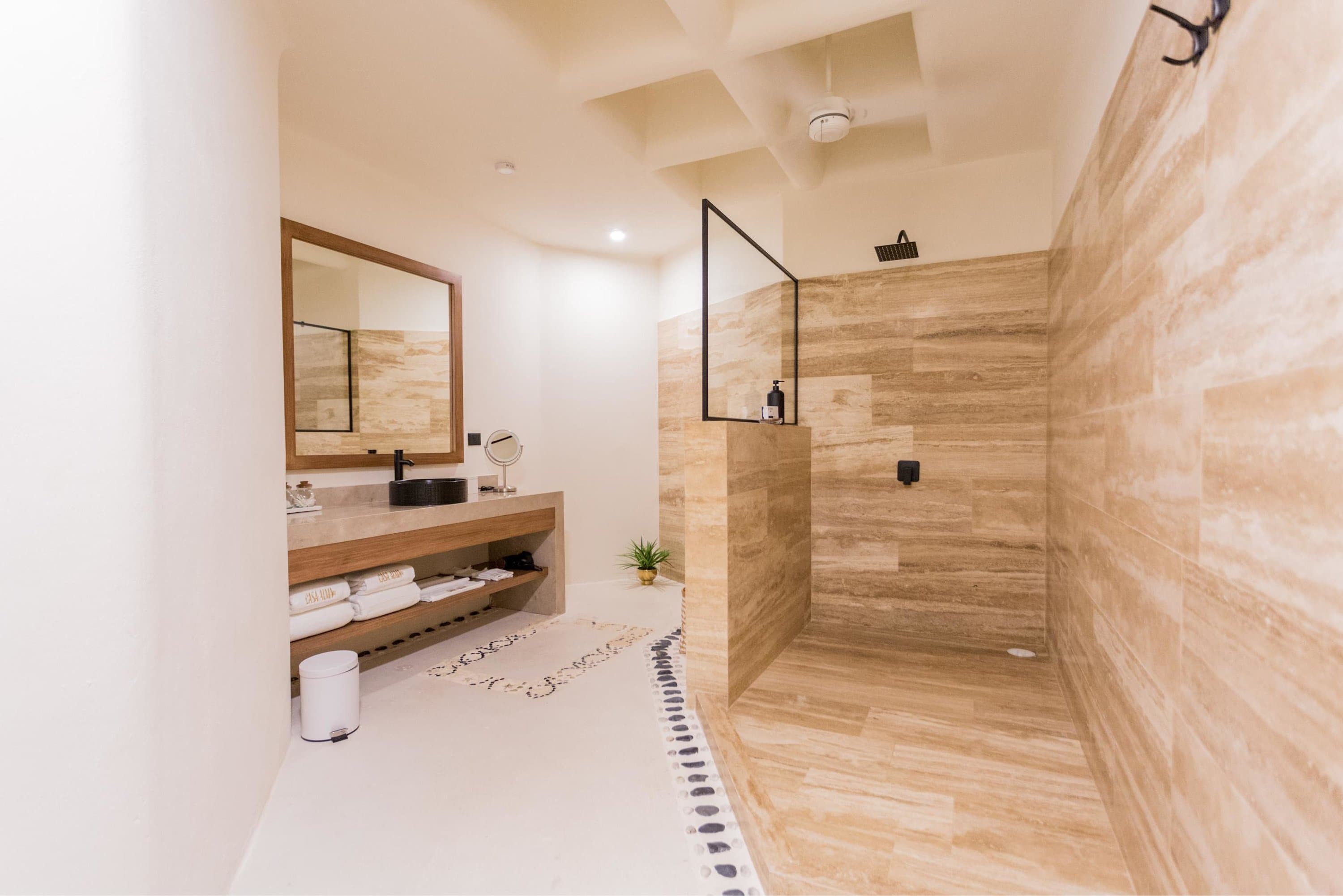 Modern bathroom with a stone-tiled walk-in shower, a floating vanity with a black sink, and a large 