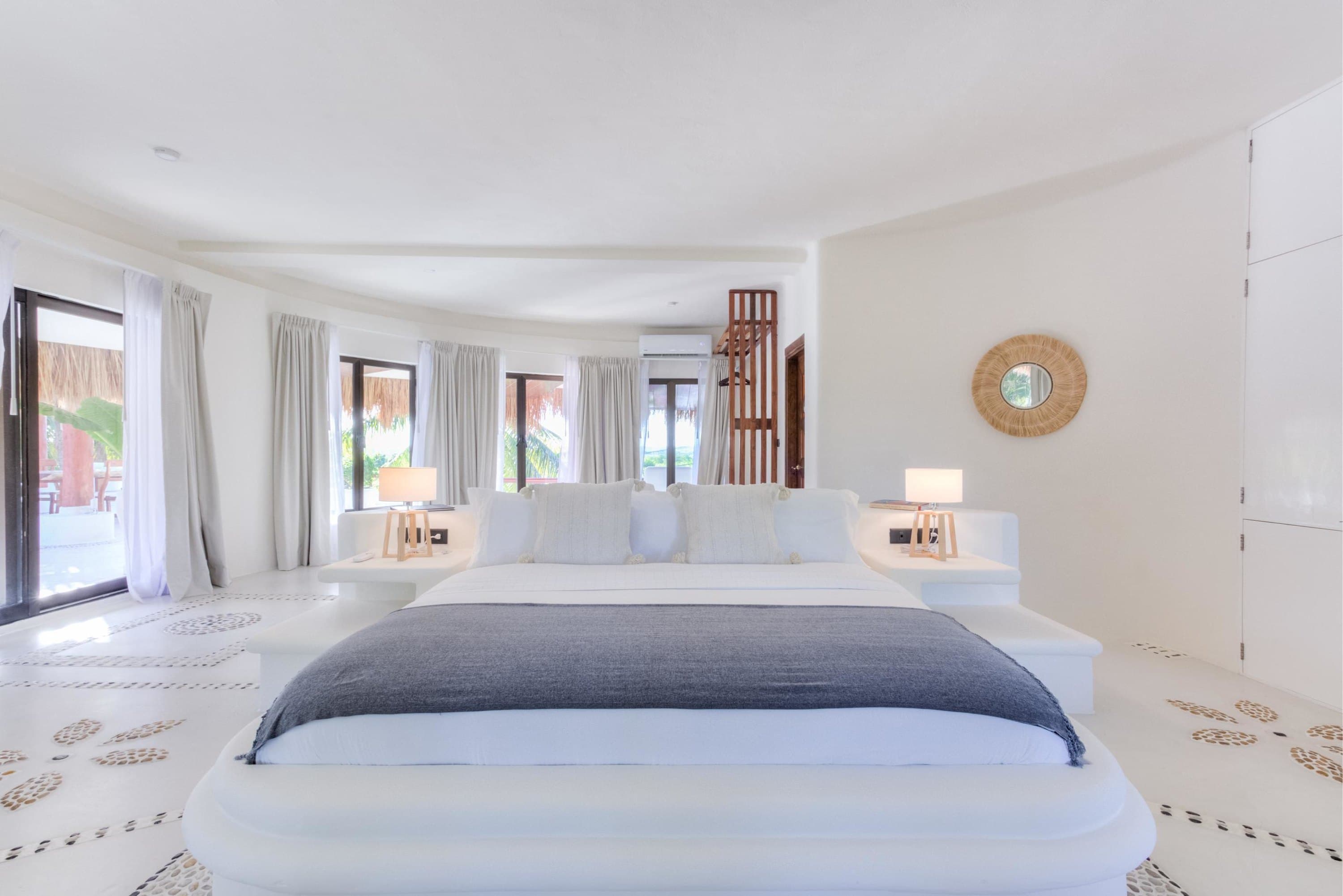 A white bedroom with a large bed and a gray blanket.