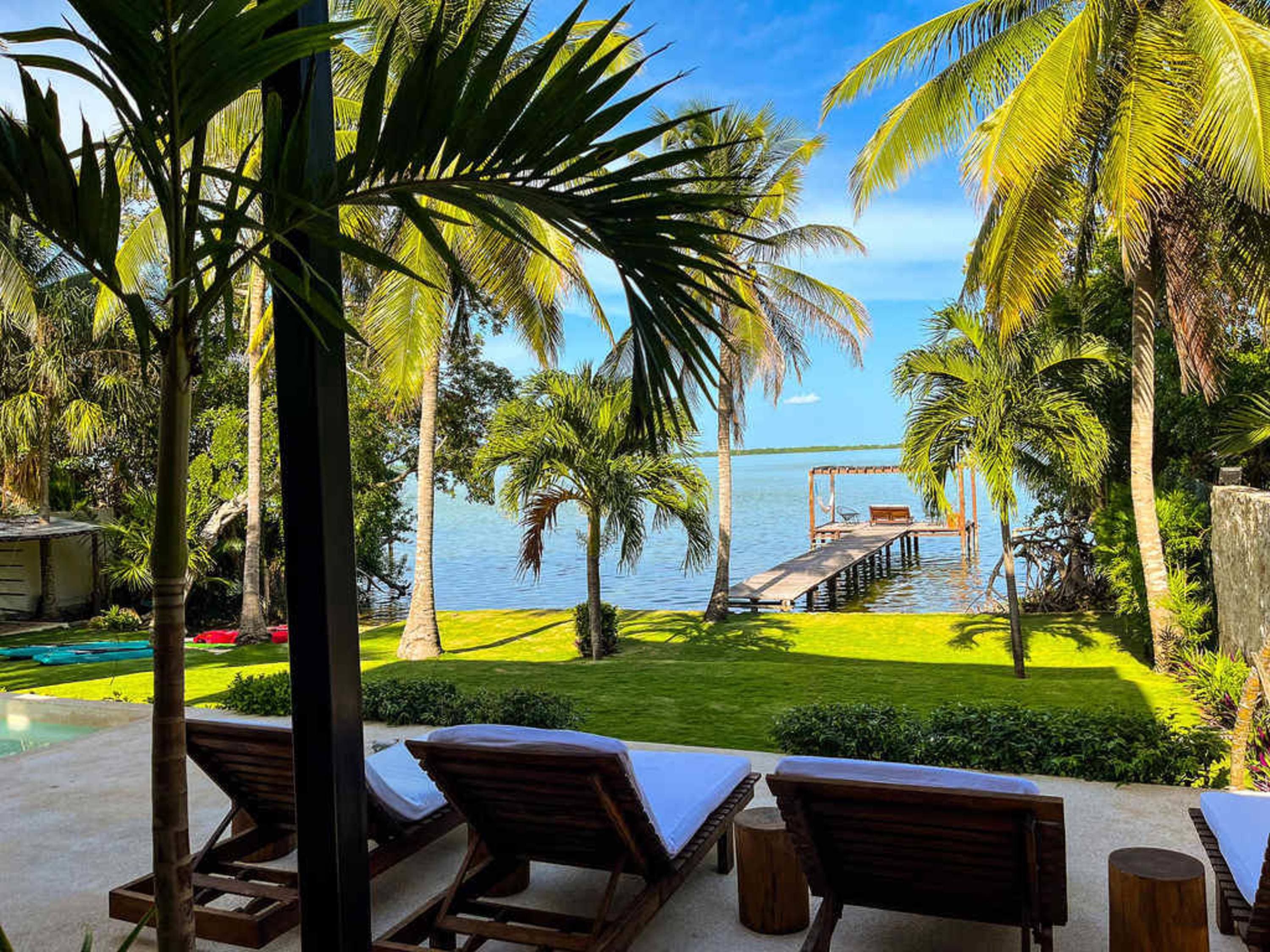 A tropical paradise with lounge chairs, a pier, and palm trees.