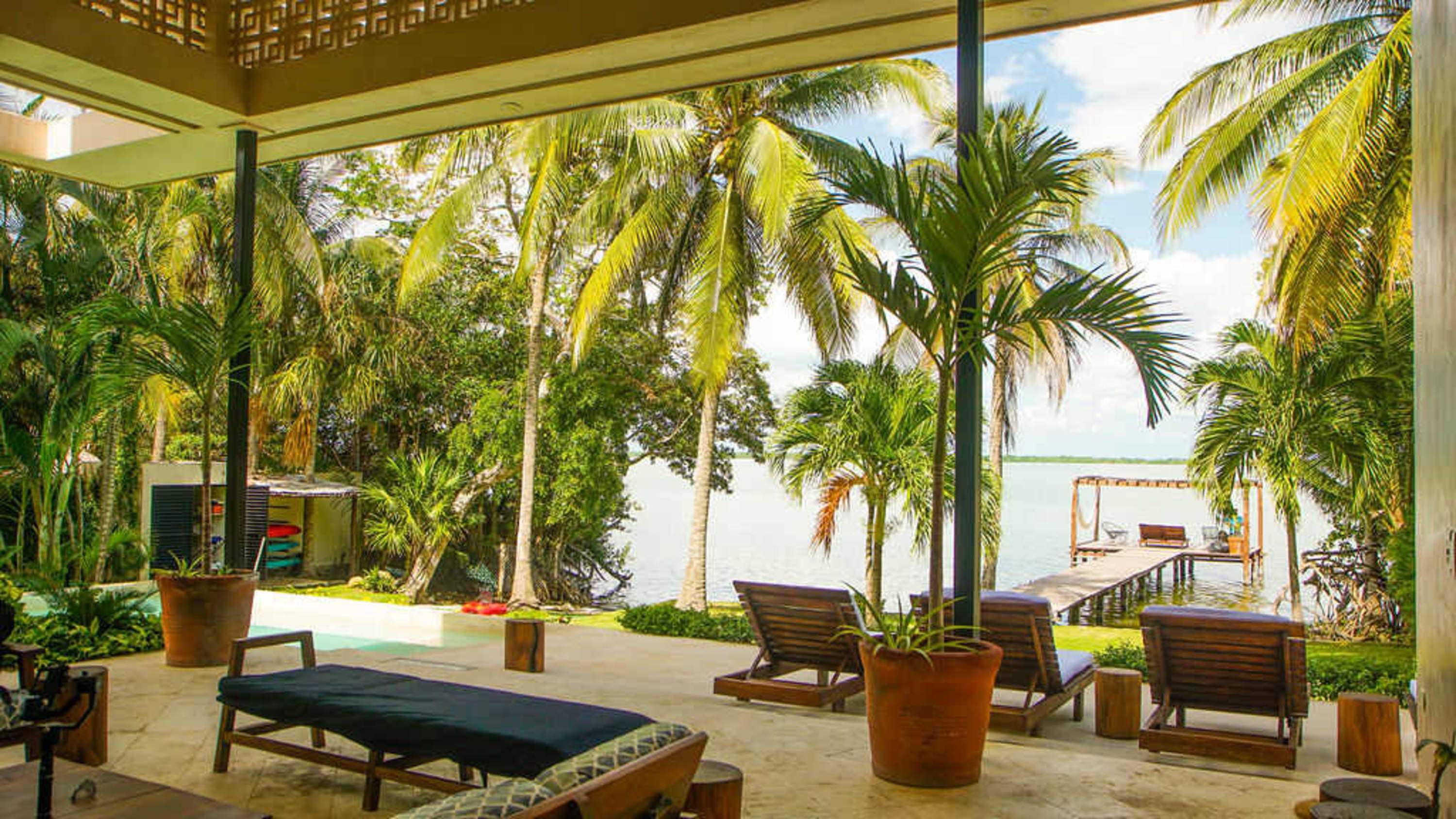 Tropical resort with lounge chairs and a dock on the water.