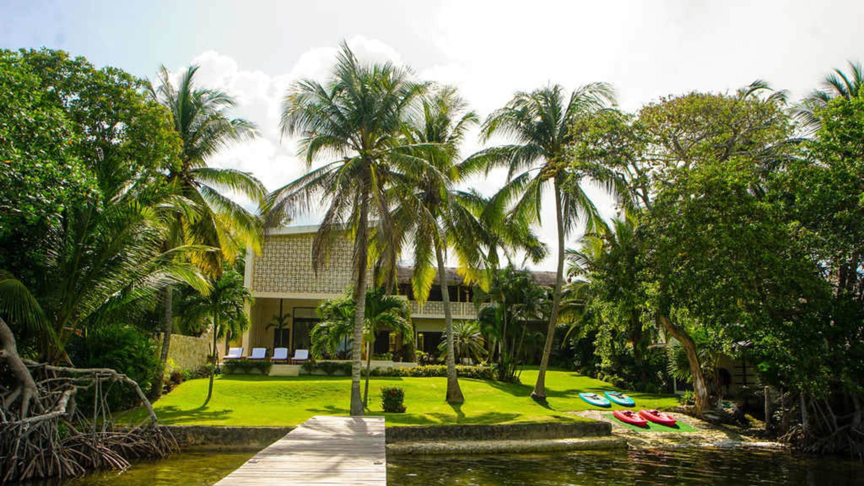 Palm trees and kayaks by a waterfront house.