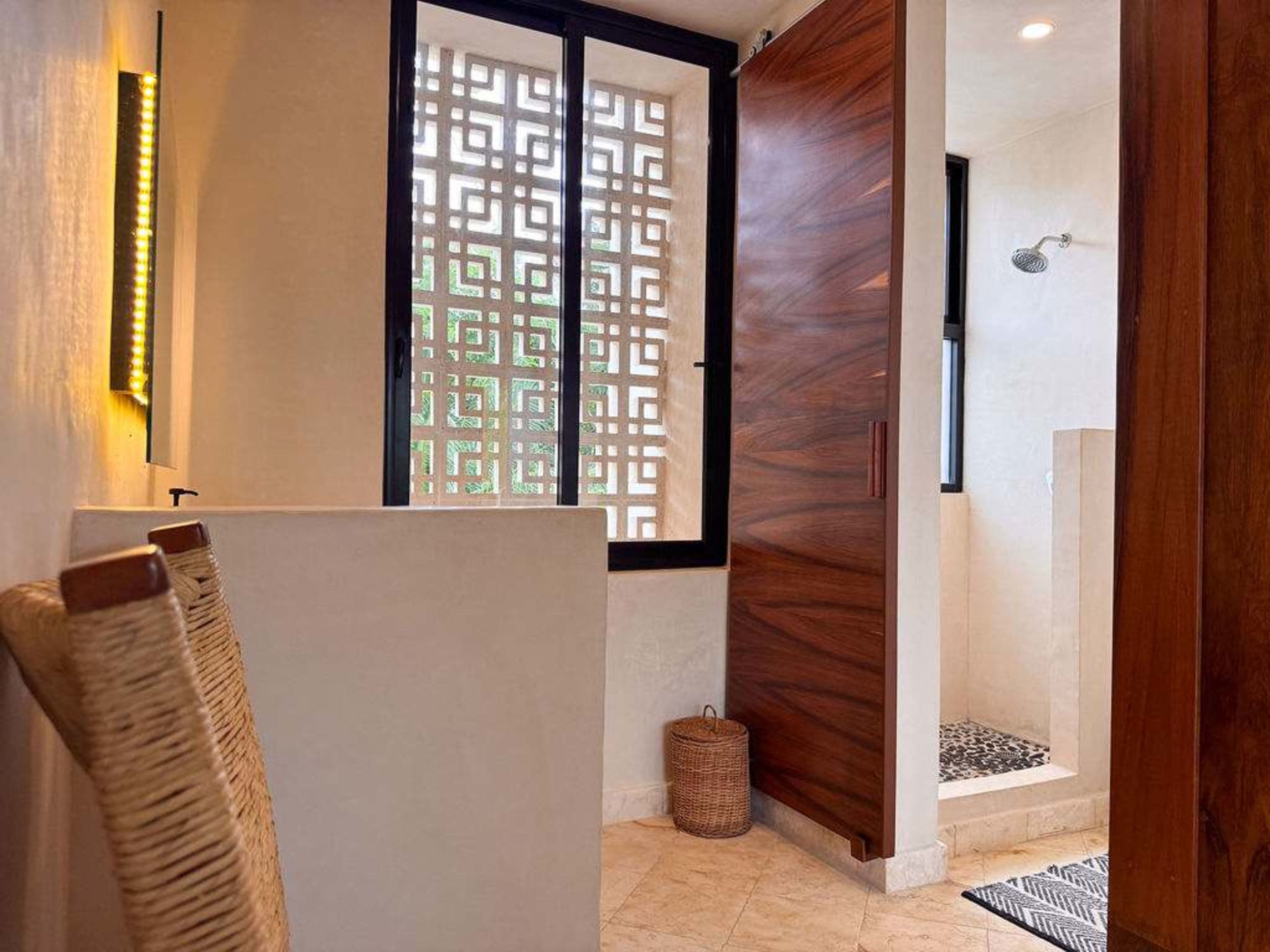 A shower stall with a patterned rug and a wooden door in a modern bathroom.