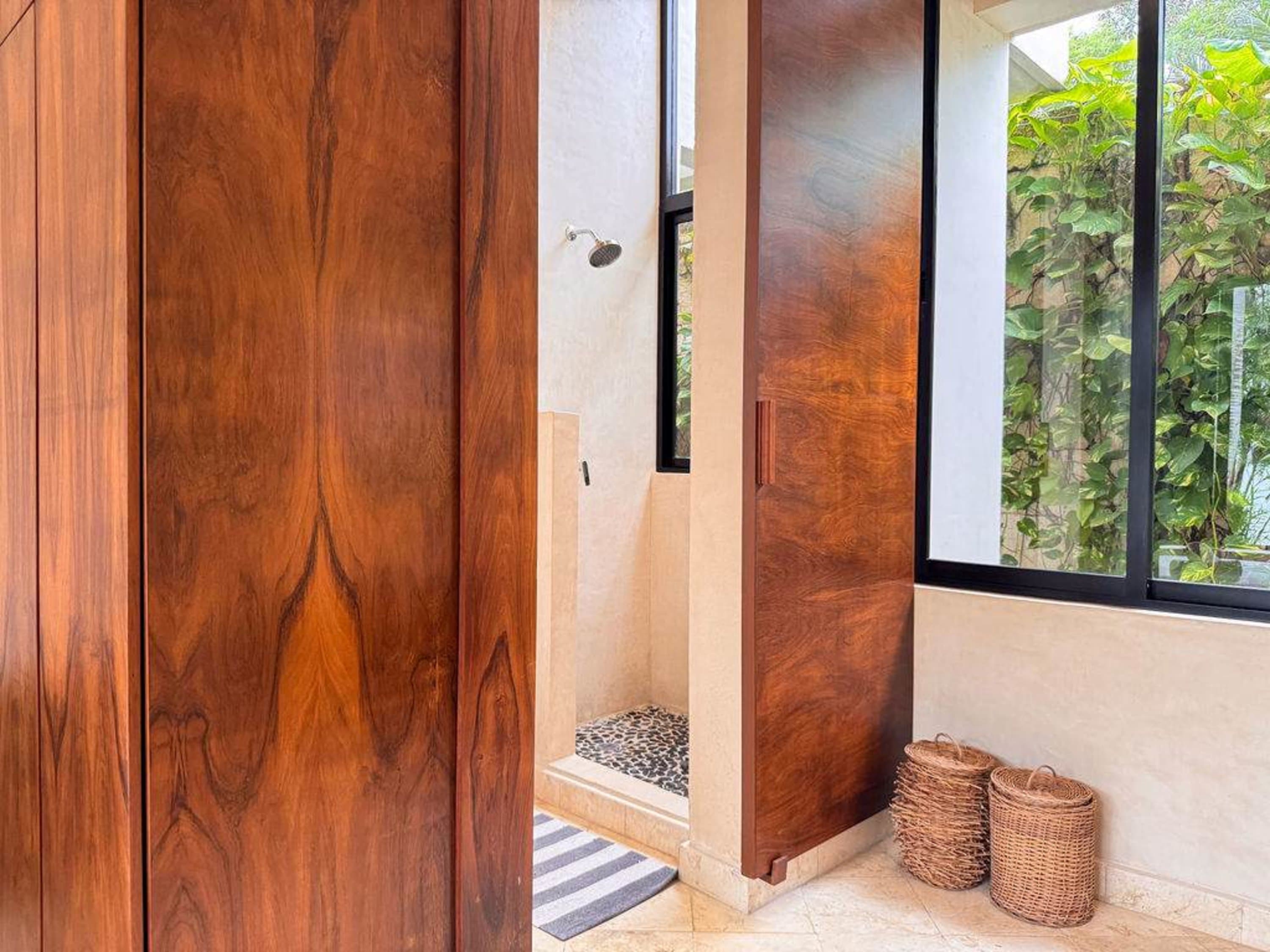 A modern bathroom with wooden doors, a shower, and large windows.