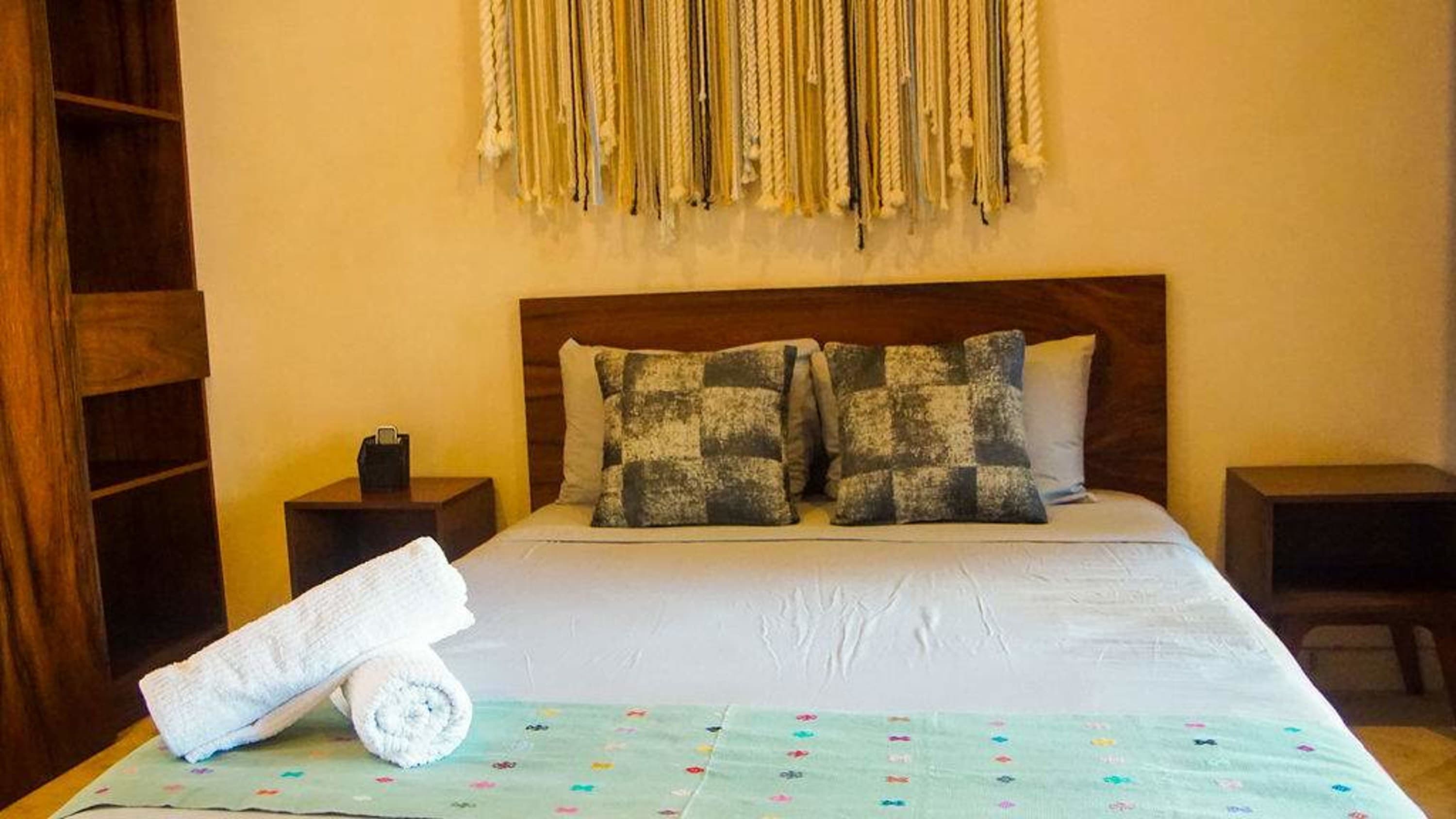 A bed with pillows, a headboard, and a throw is shown.