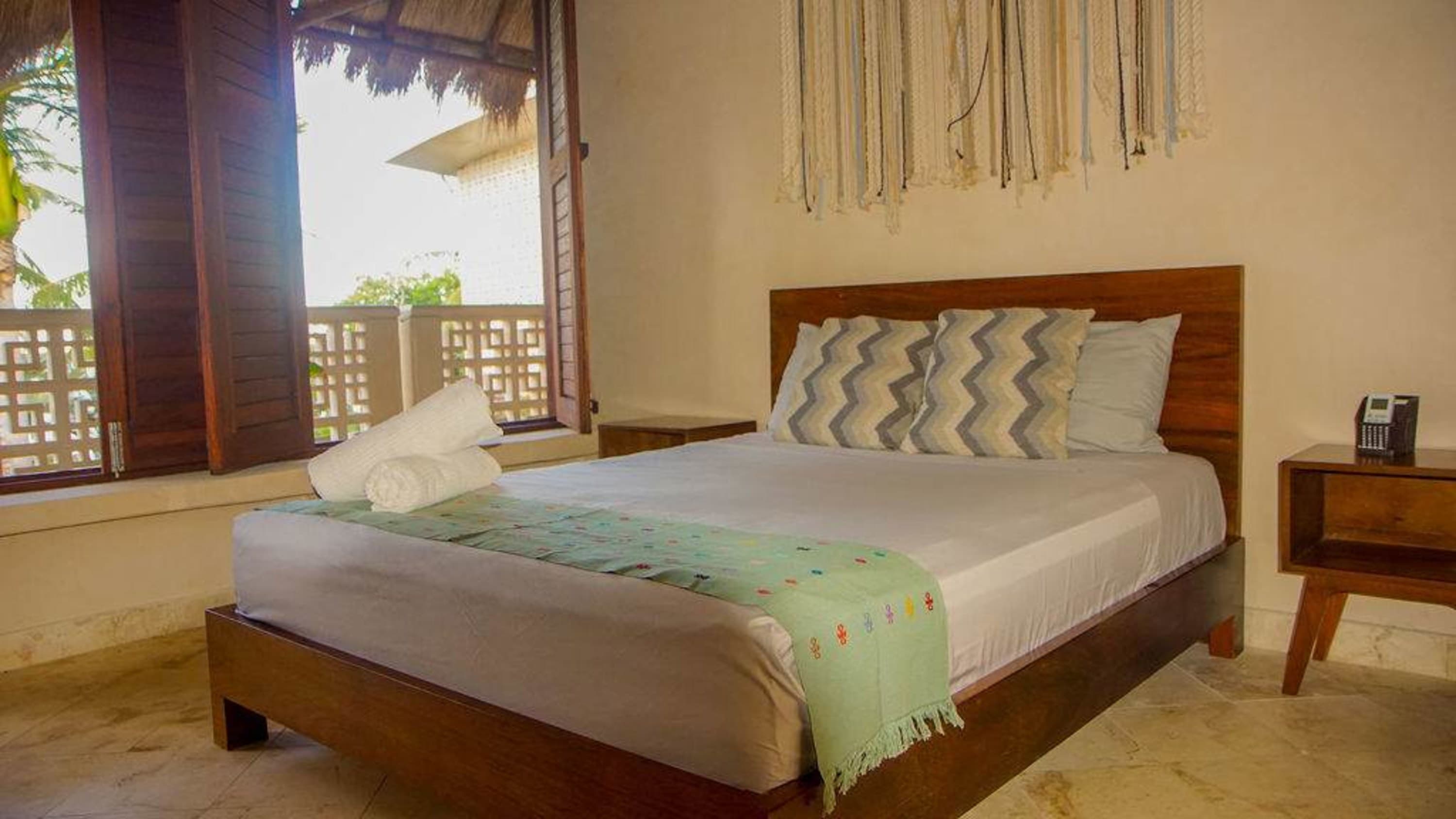 A bedroom with a wooden bed, pillows, and a decorative wall hanging.