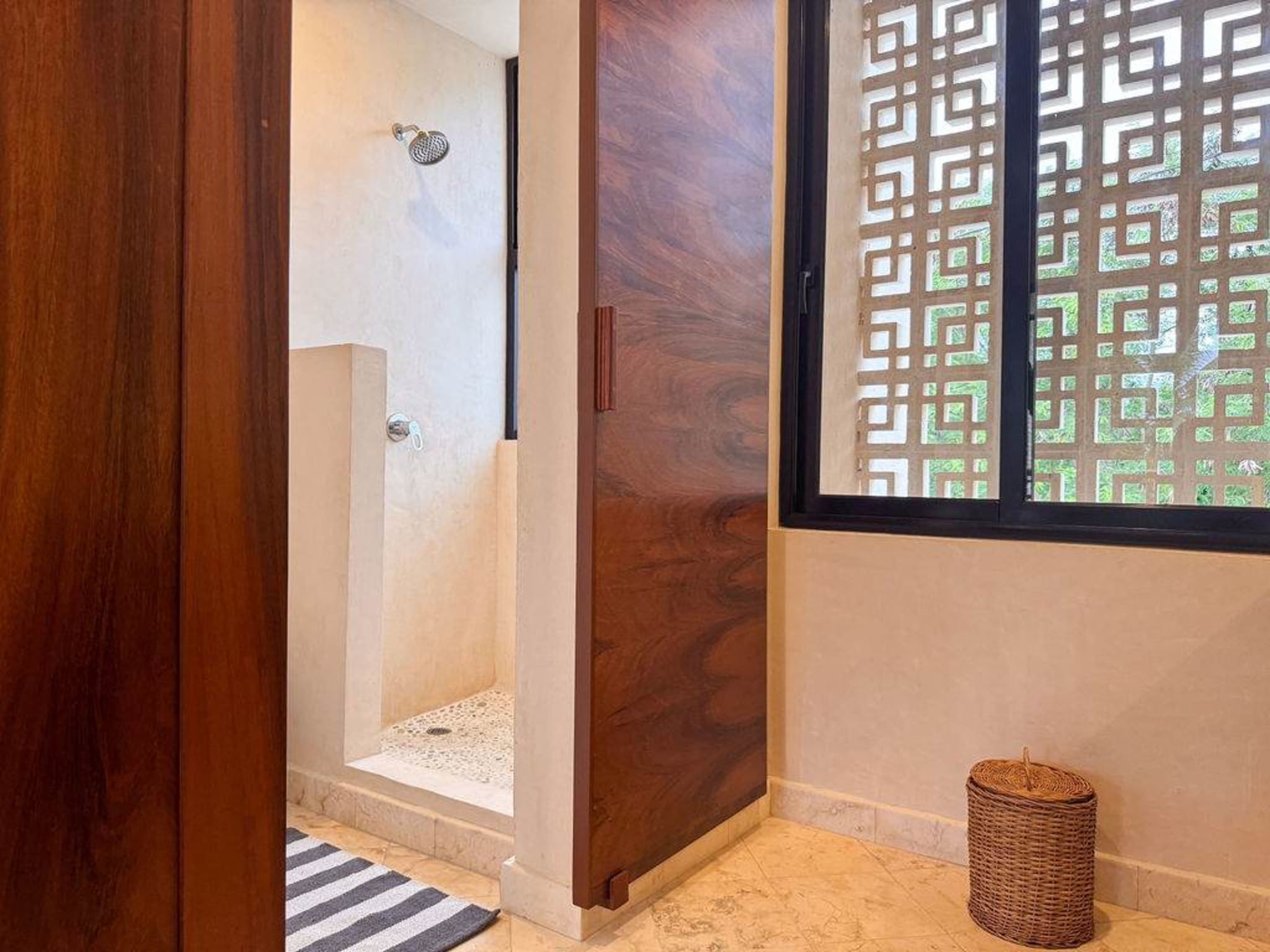 A modern bathroom with a glass-enclosed shower, wood accents, and a unique decorative window.