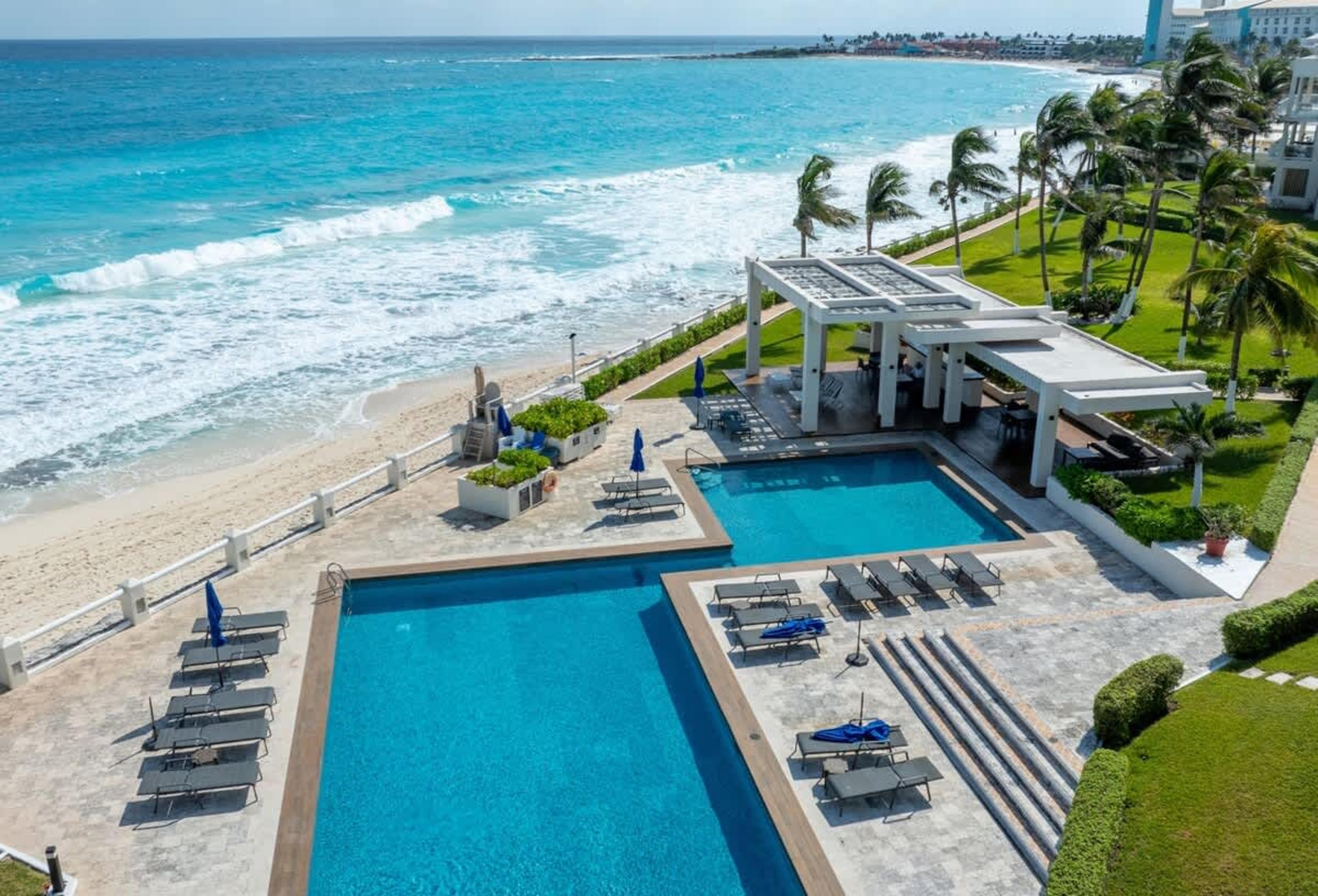 Oceanfront resort with pools, loungers, and palm trees.