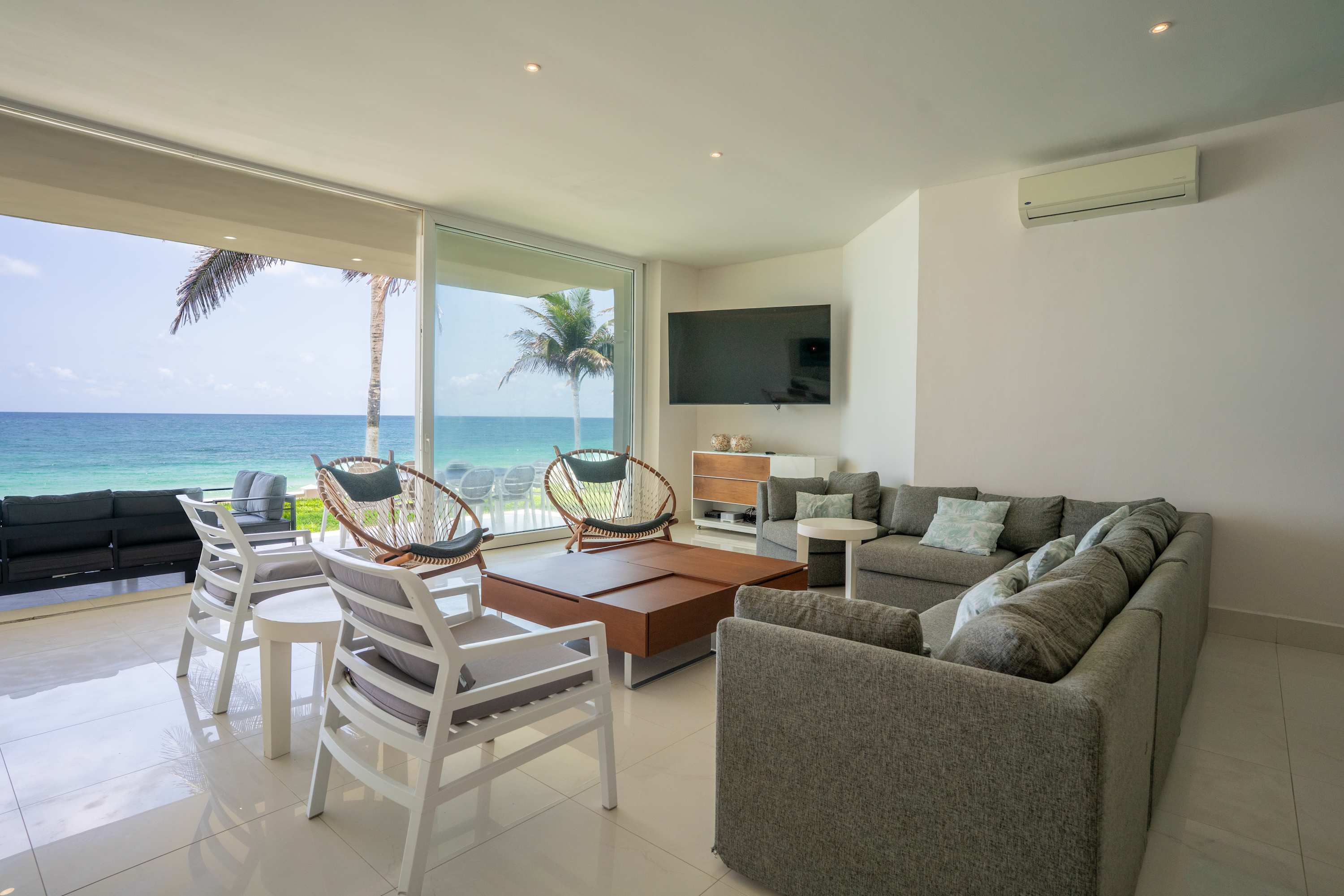 Living room with a view of the ocean and palm trees.