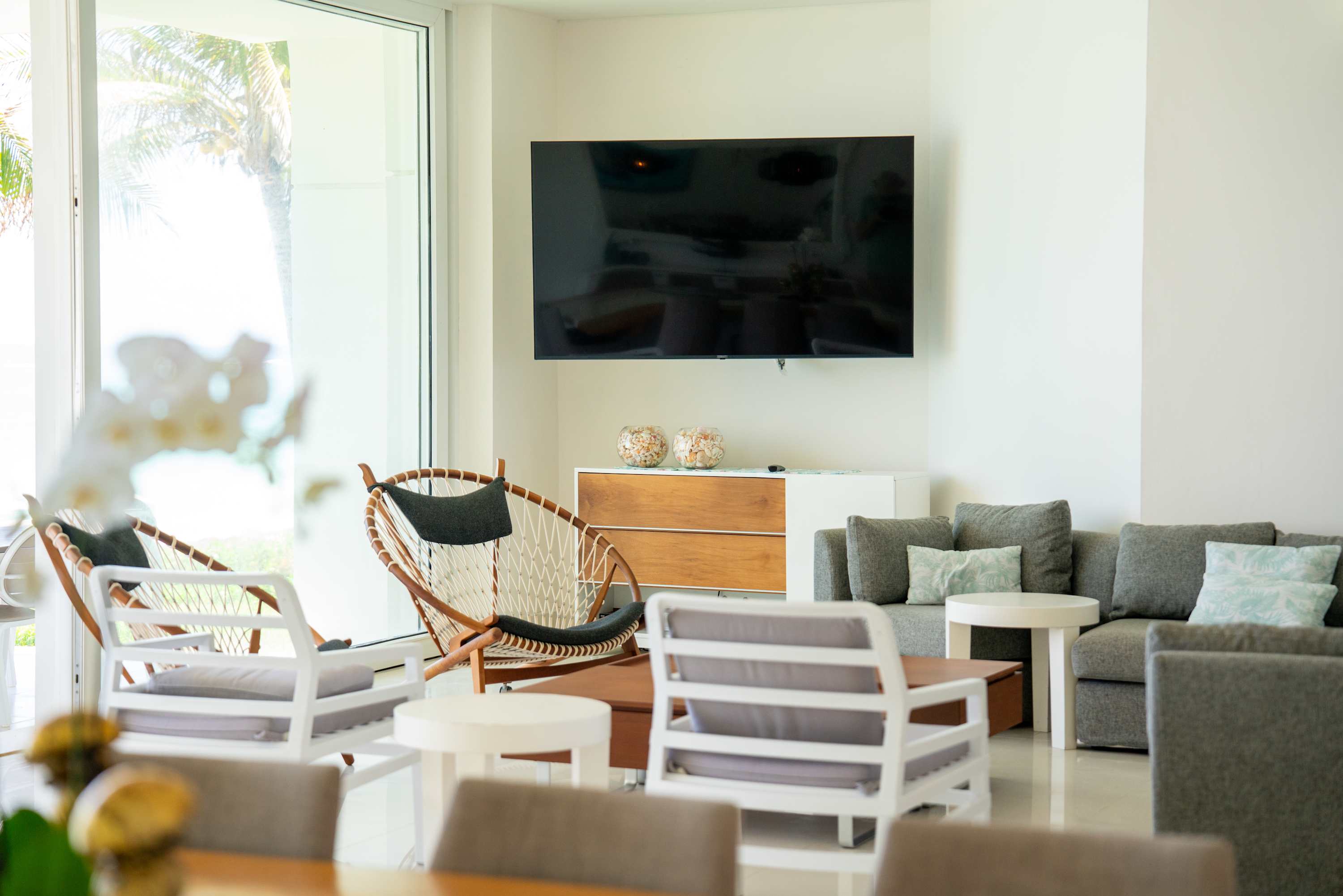 Modern living room with grey couches, accent chairs, and a TV.