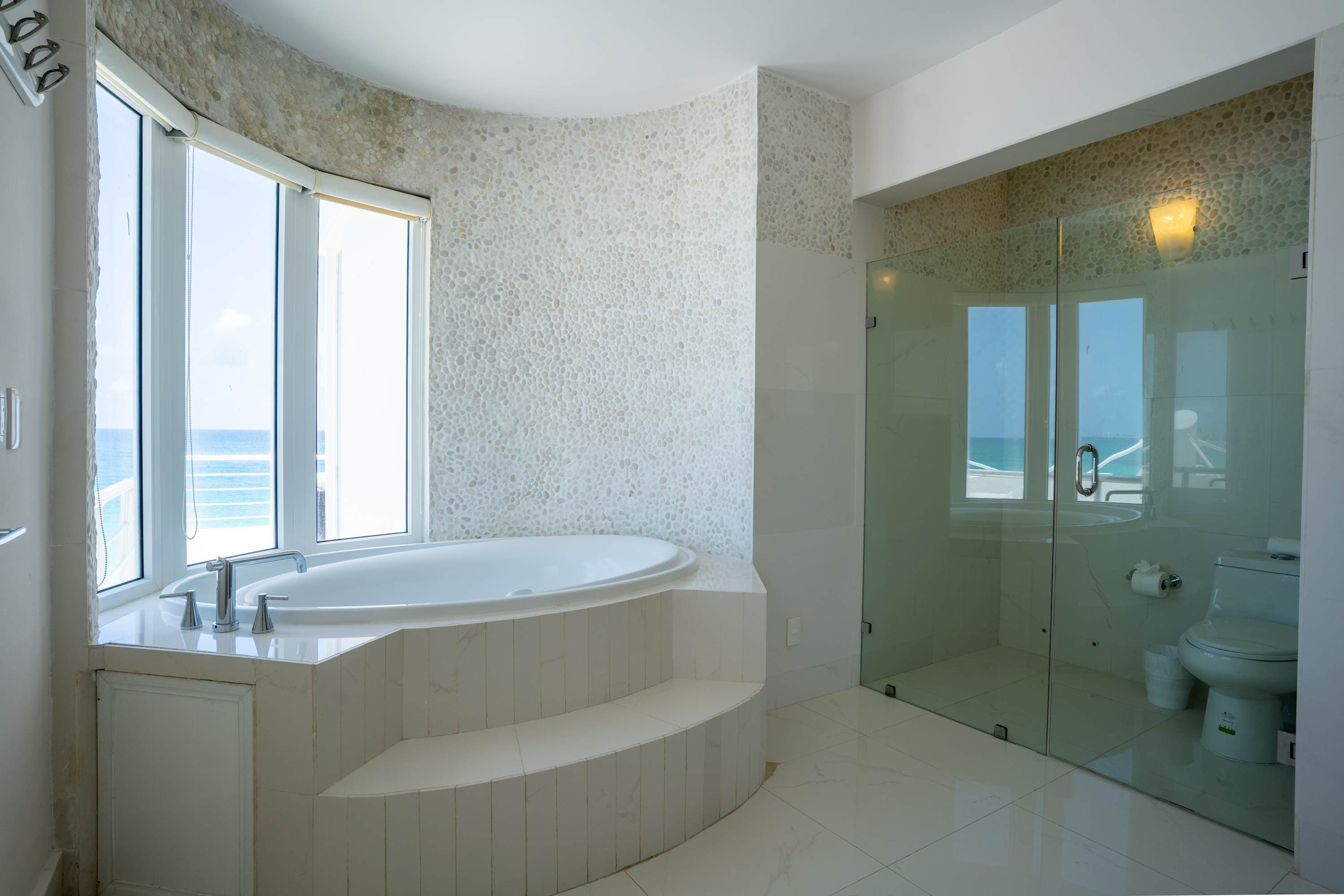 A luxurious bathroom with a bathtub and shower, offering ocean views.