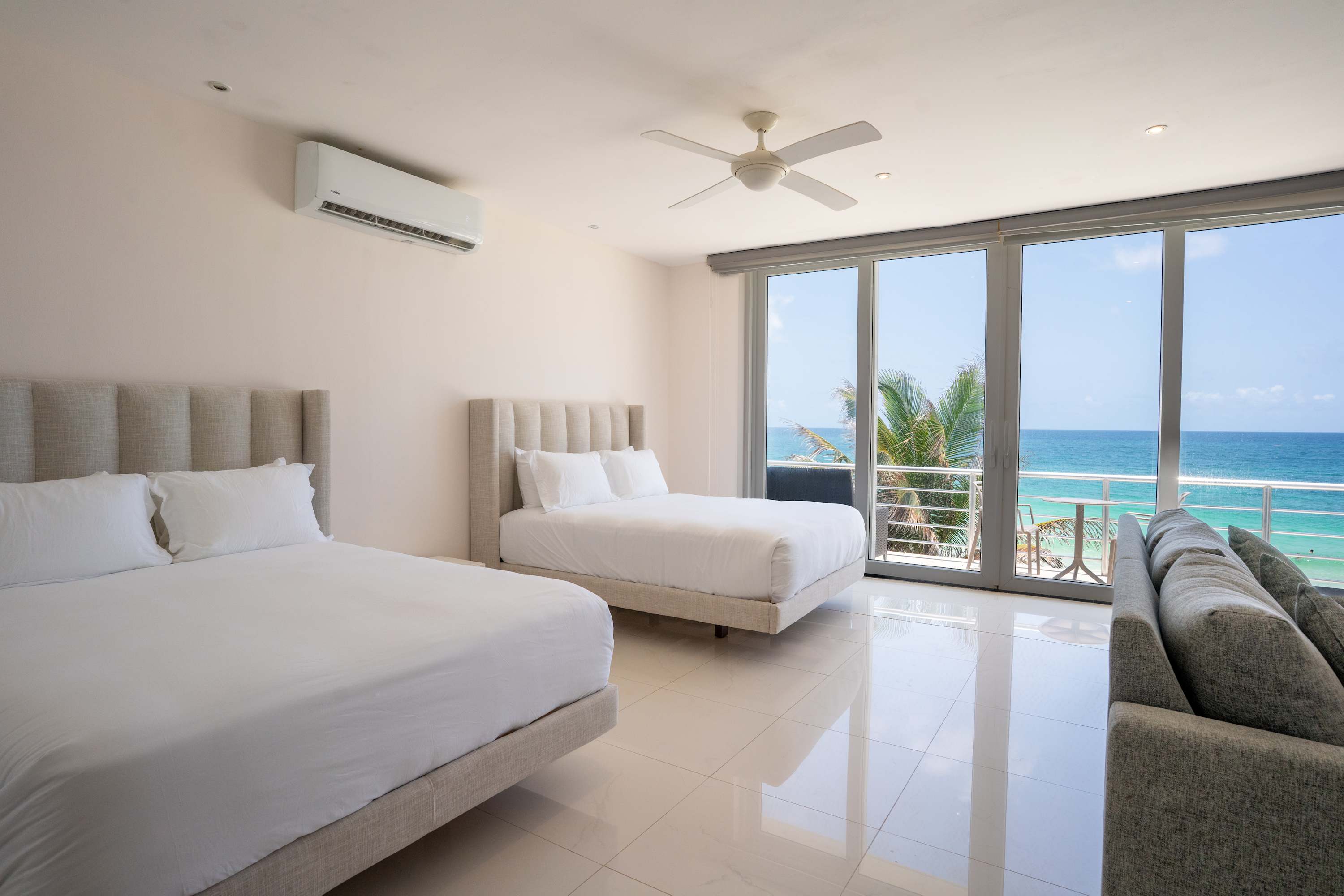 A hotel room with two beds, a sofa, and a view of the ocean.