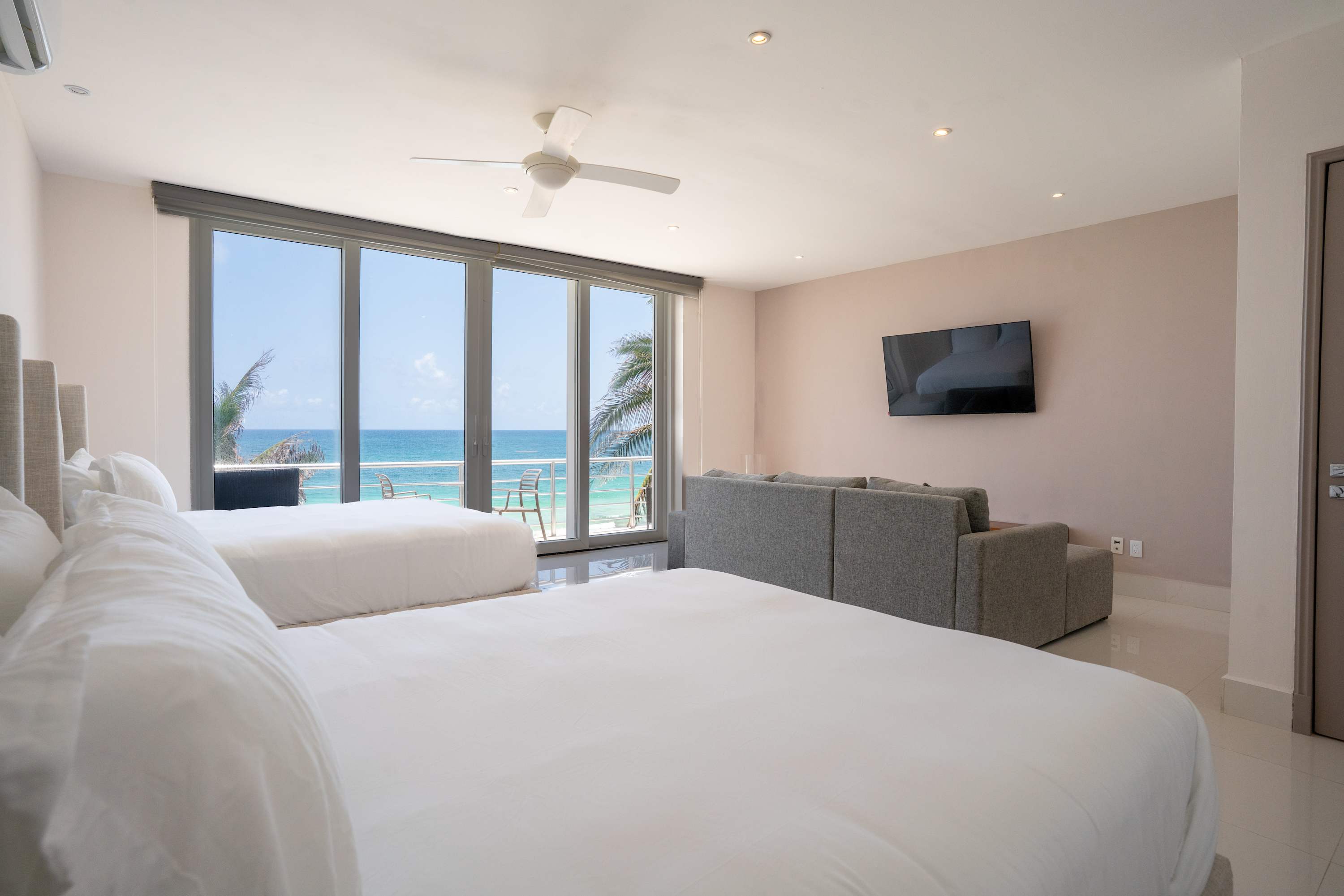 A hotel room with two beds and a balcony overlooking the ocean.
