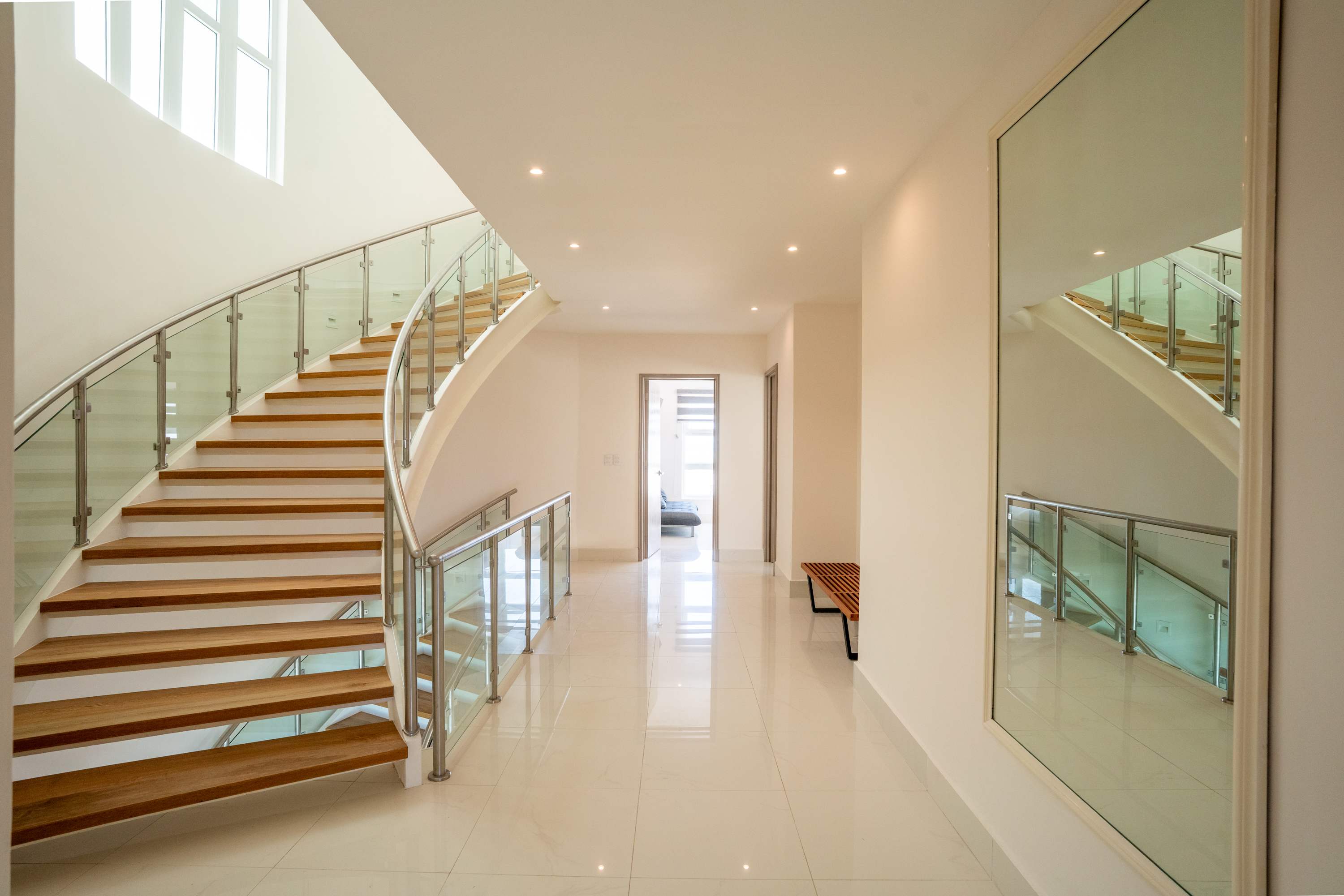 Modern hallway with a curved staircase and a large mirror.