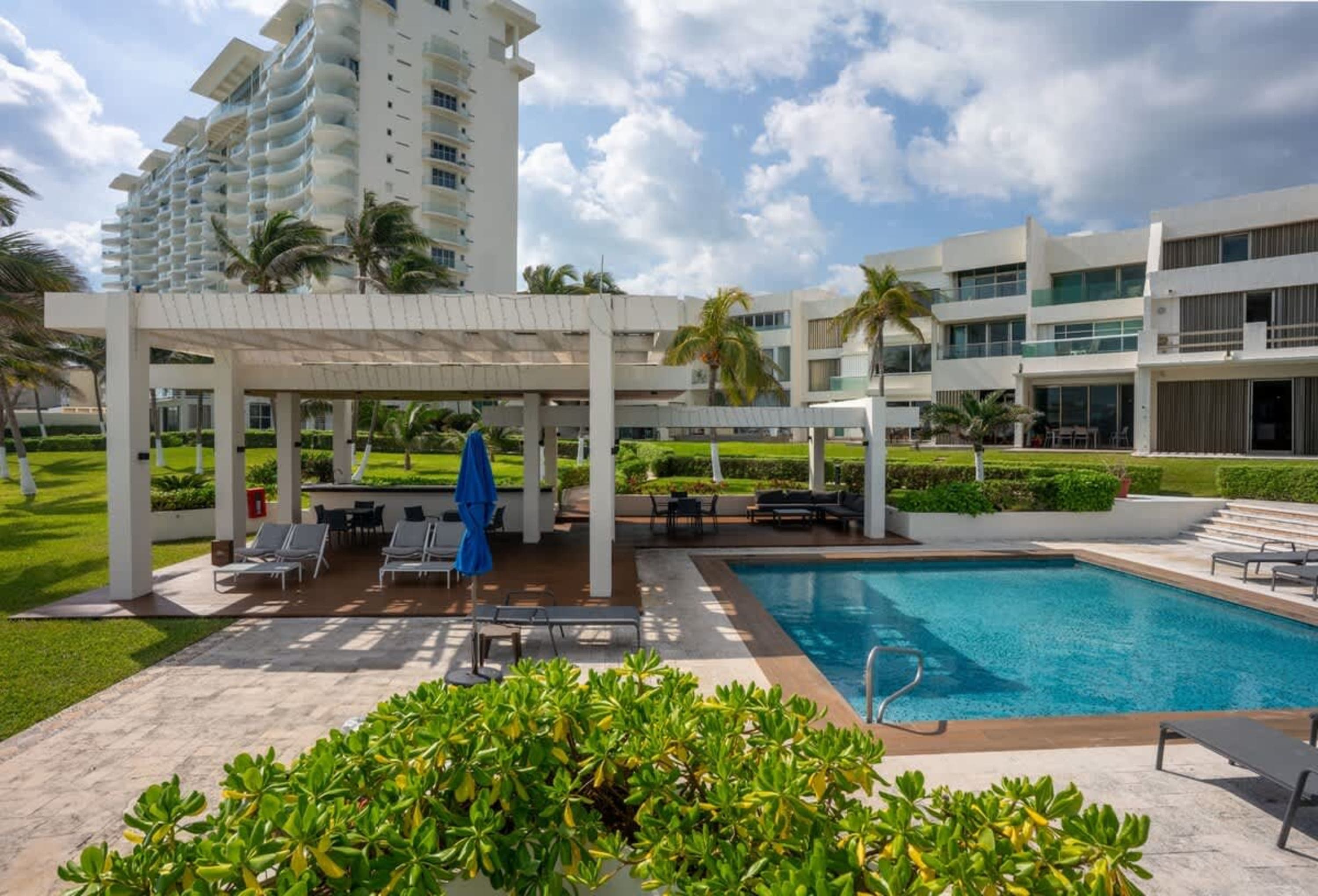 A resort pool with lounge chairs and a covered patio.