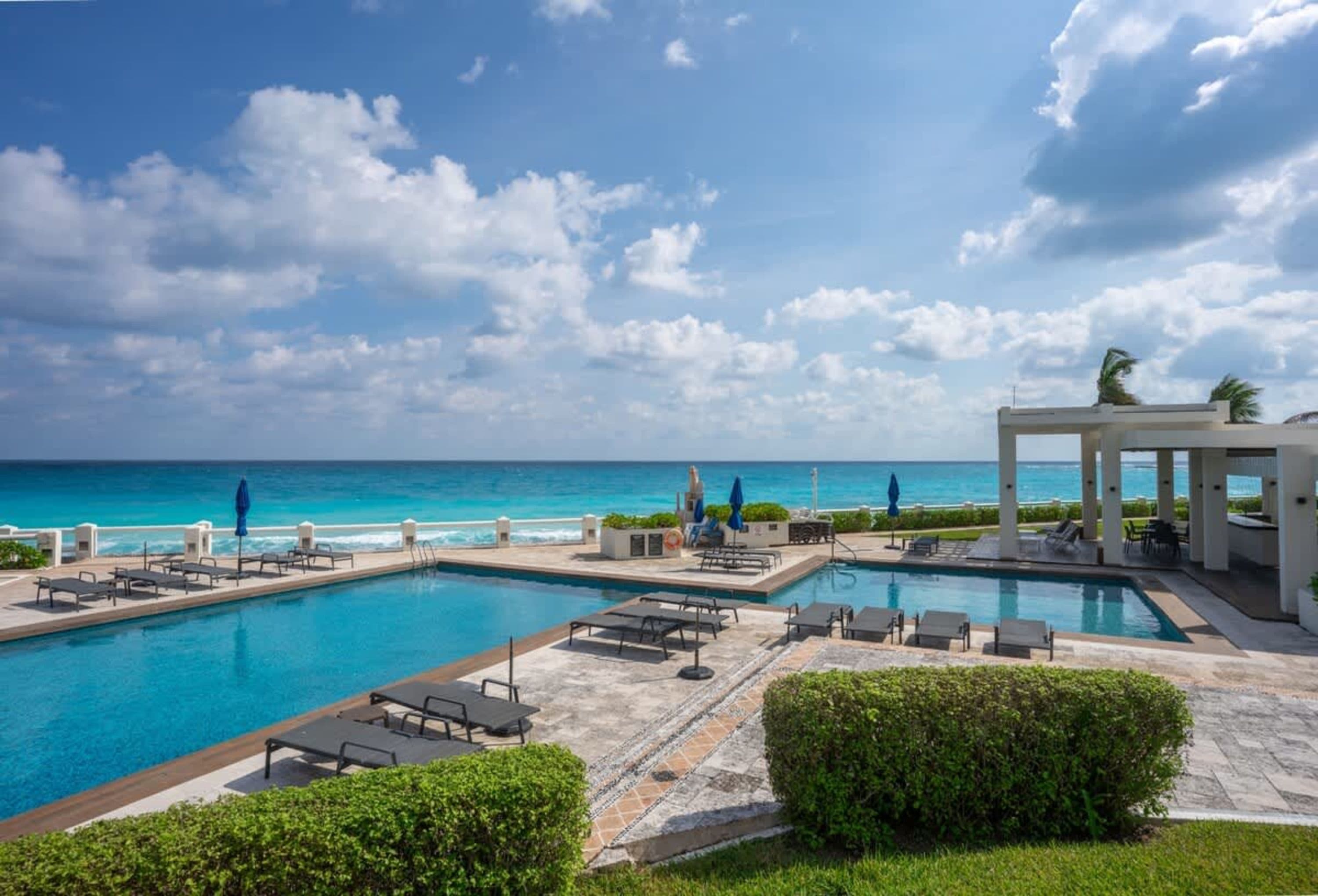 Luxury resort with pool, lounge chairs, and ocean view
