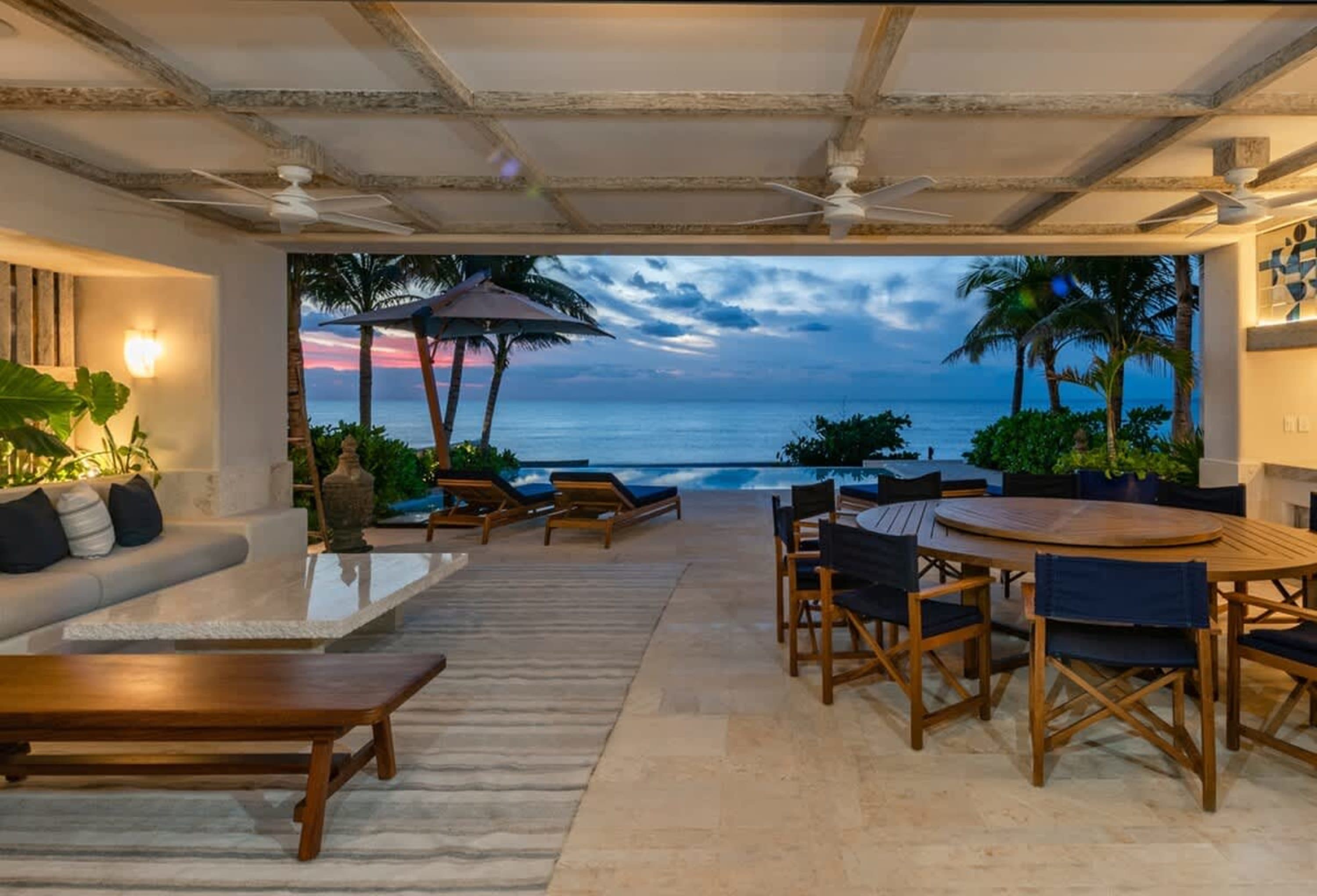 A stunning outdoor patio with a dining set, lounge chairs, and a pool overlooking the ocean.