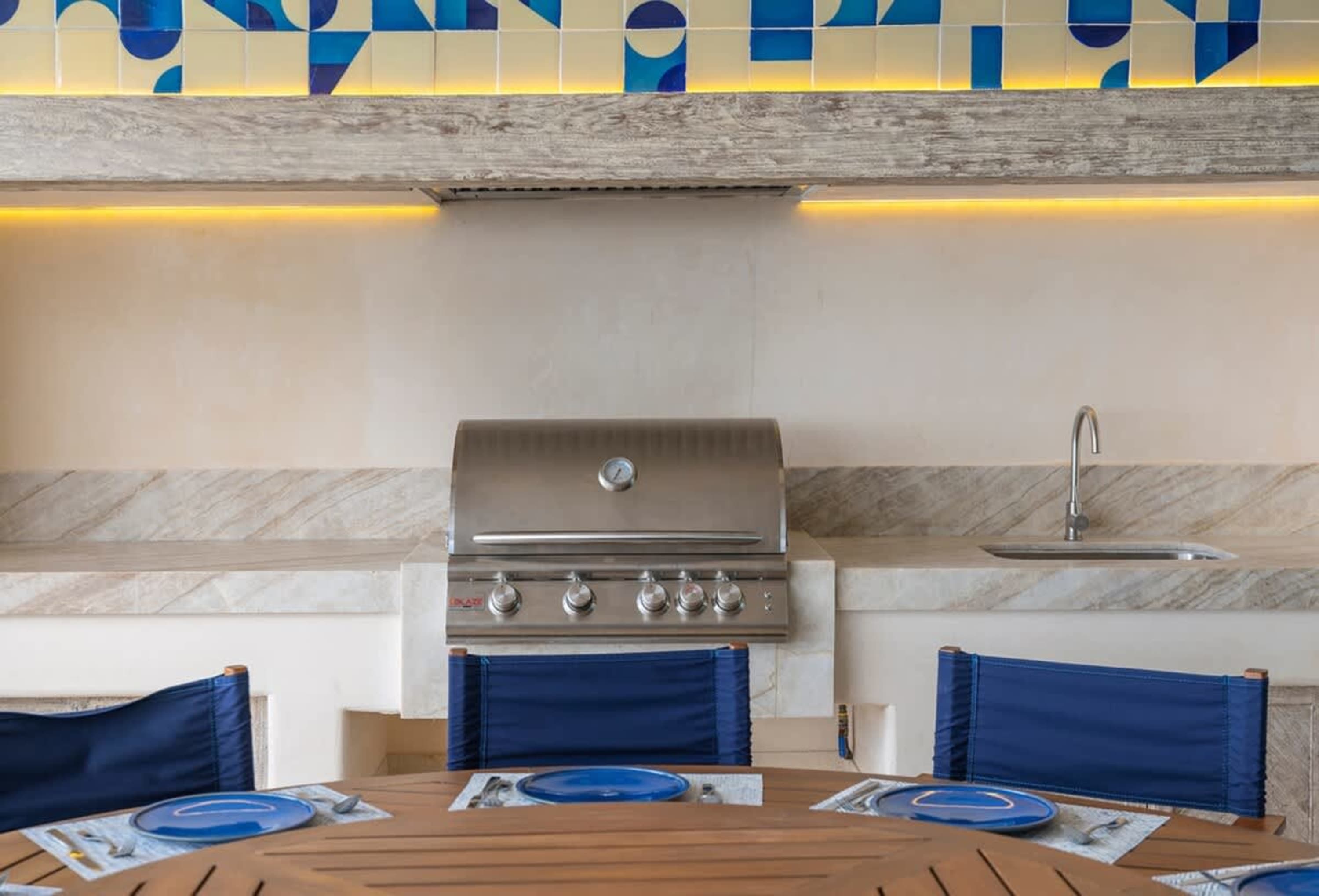 Outdoor kitchen with grill, sink, and a table set for dining.