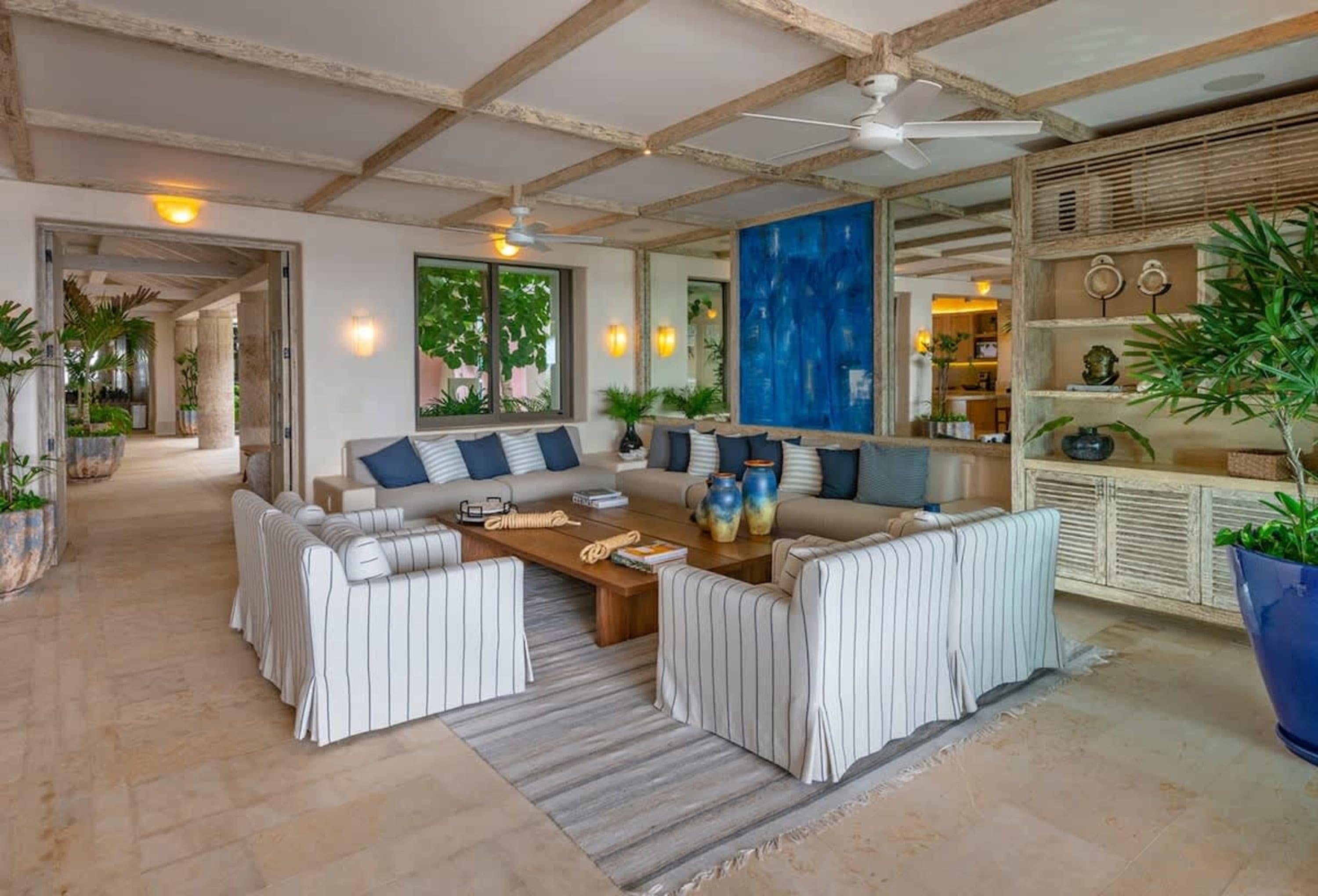 A living room with light-colored flooring, a sectional sofa with blue pillows, and a wooden coffee t