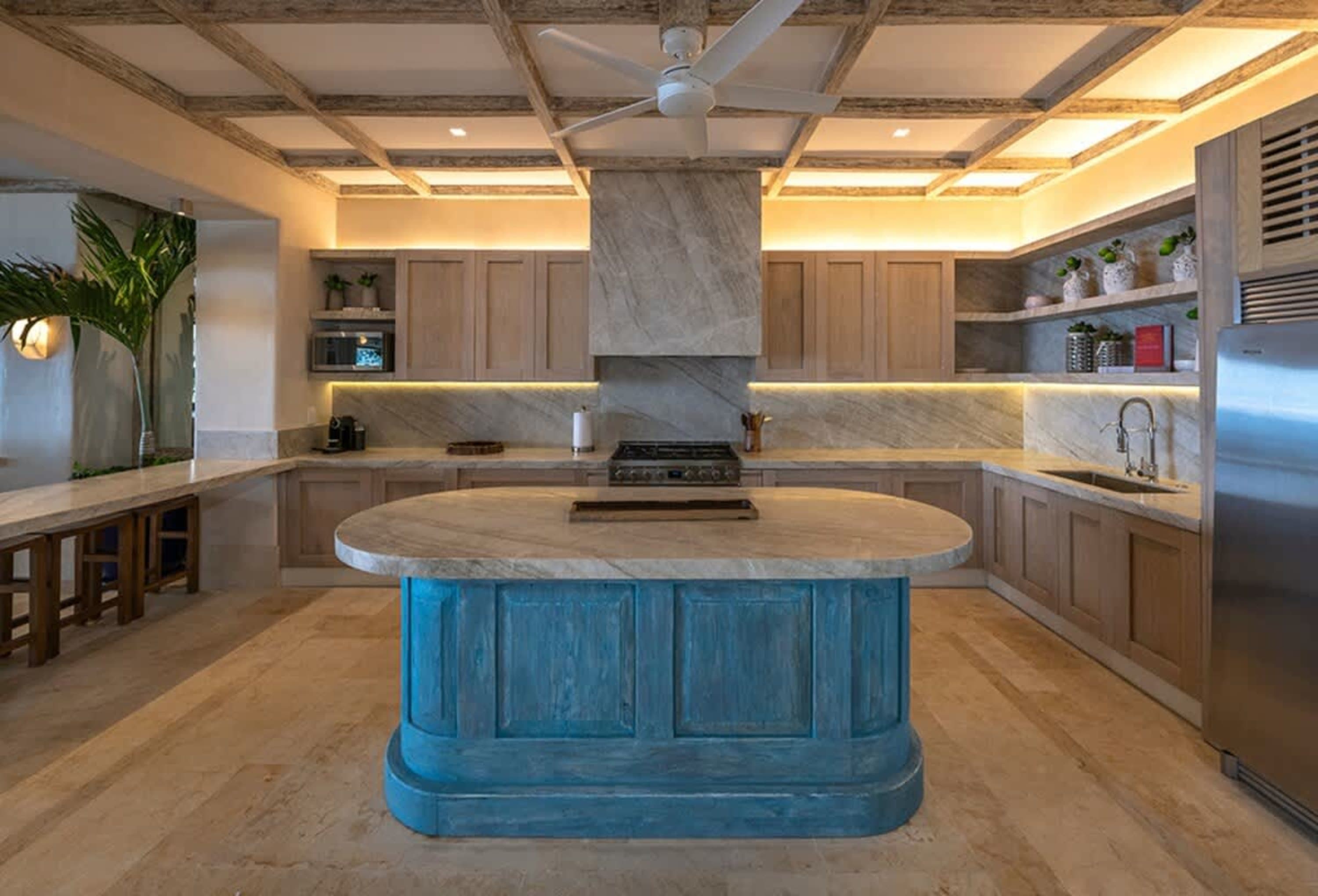 Kitchen with wooden cabinets, marble countertops, and a blue island.