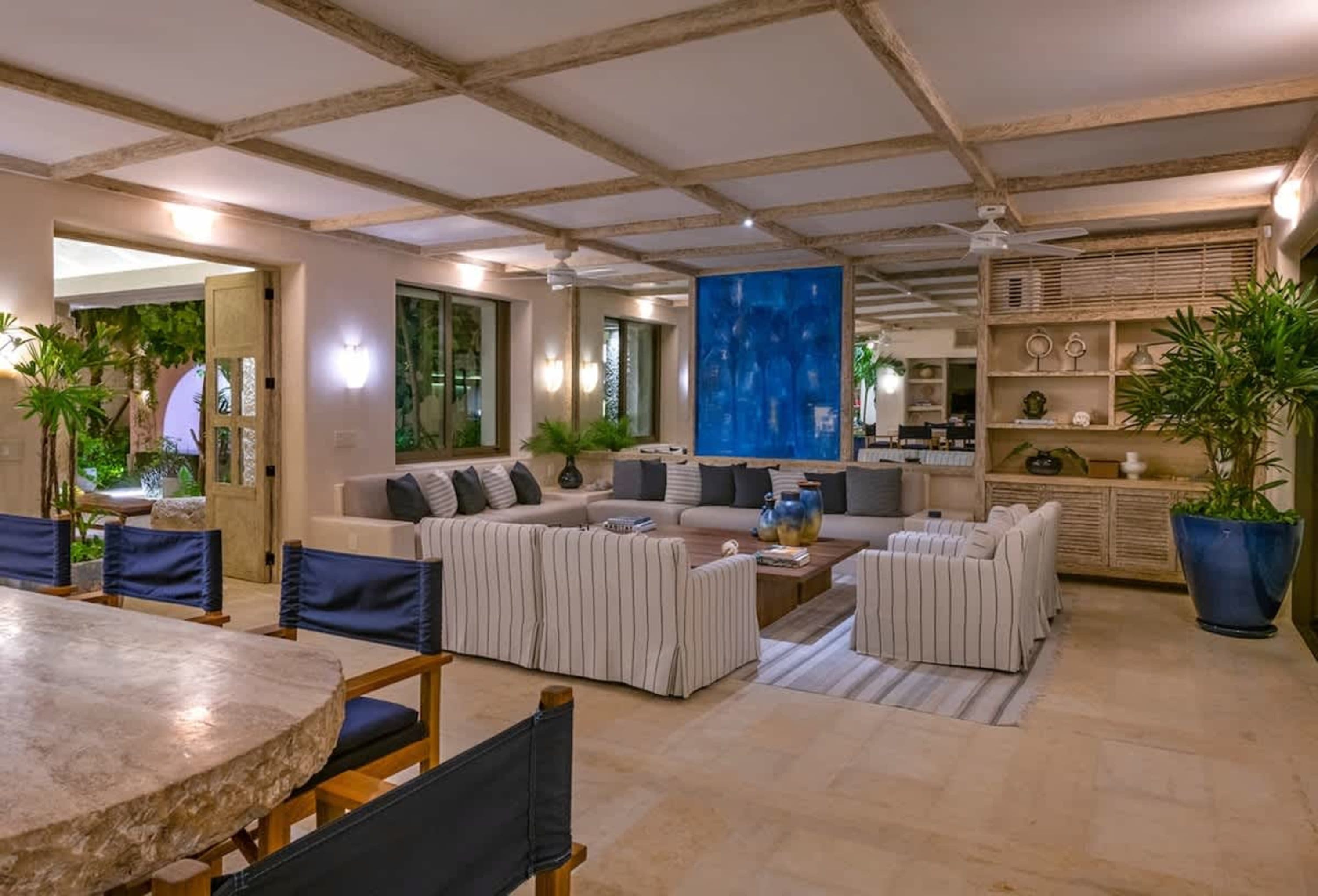 A living room with a large sectional sofa, striped armchairs, and a rough-hewn stone coffee table.