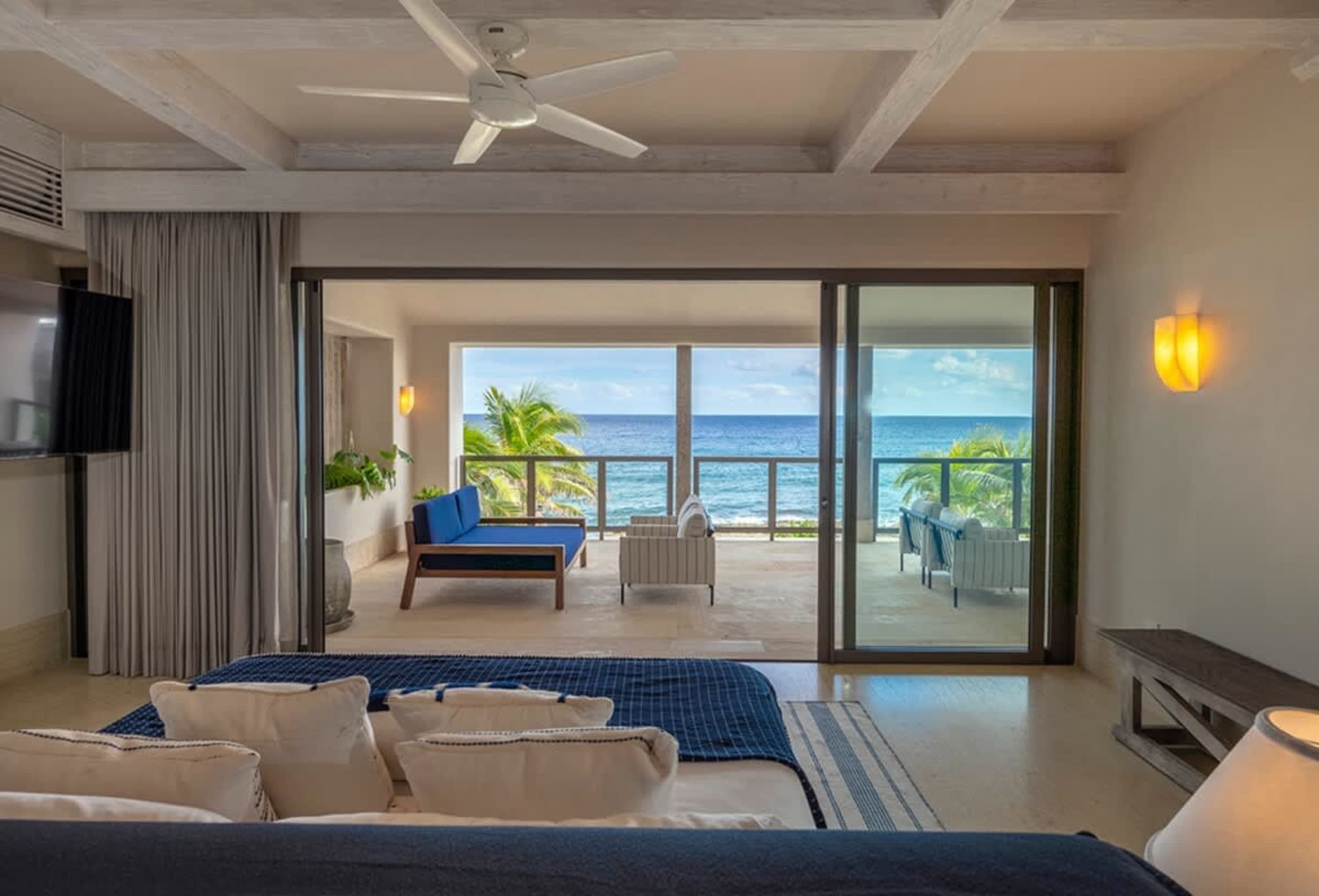 Bedroom with a view of the ocean, including a balcony with seating.
