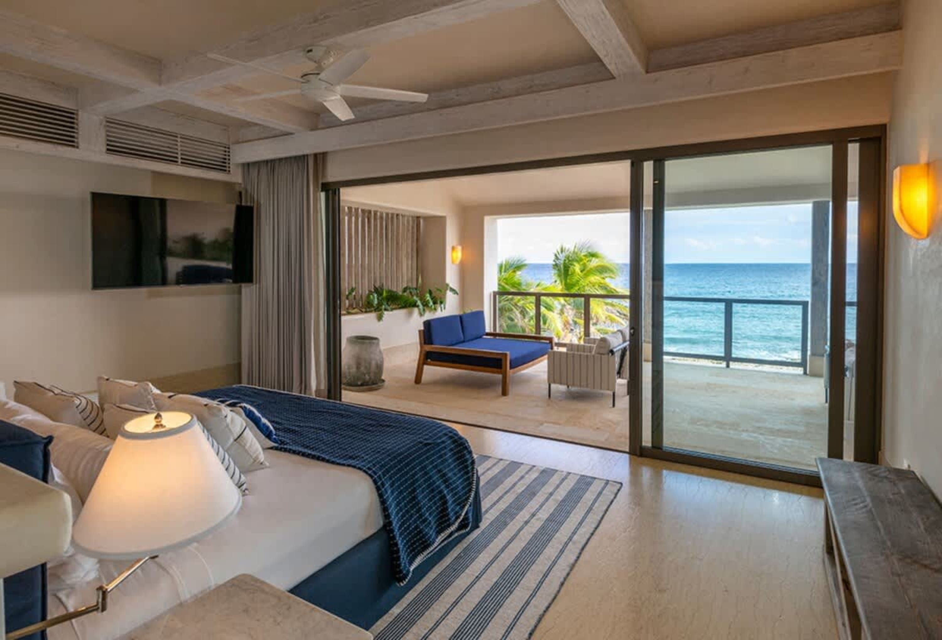 Bedroom with a view of the ocean, featuring a bed, balcony, and seating area.