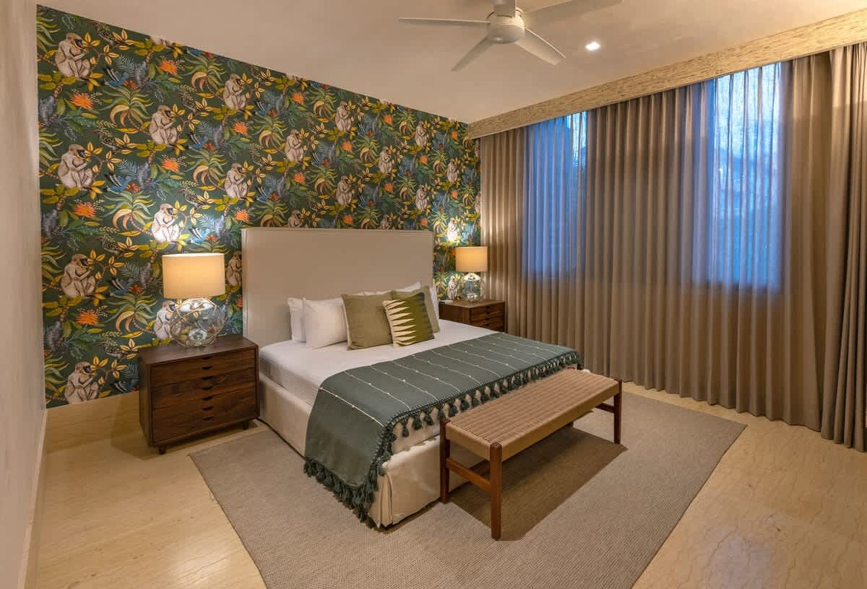 A cozy bedroom with monkey-themed wallpaper, a plush bed, and elegant curtains.