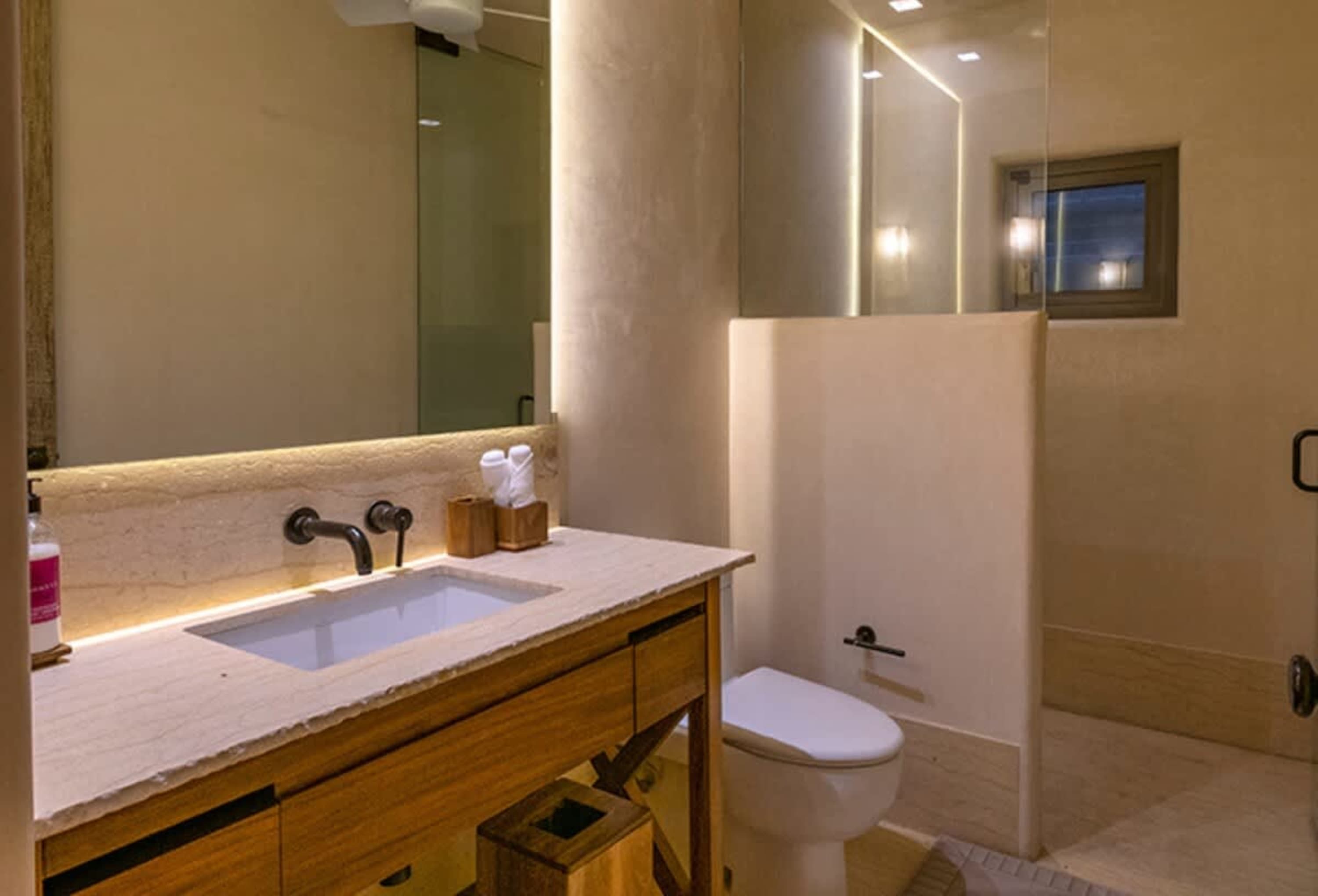 Modern bathroom with a vanity, sink, toilet, and a glass-enclosed shower.