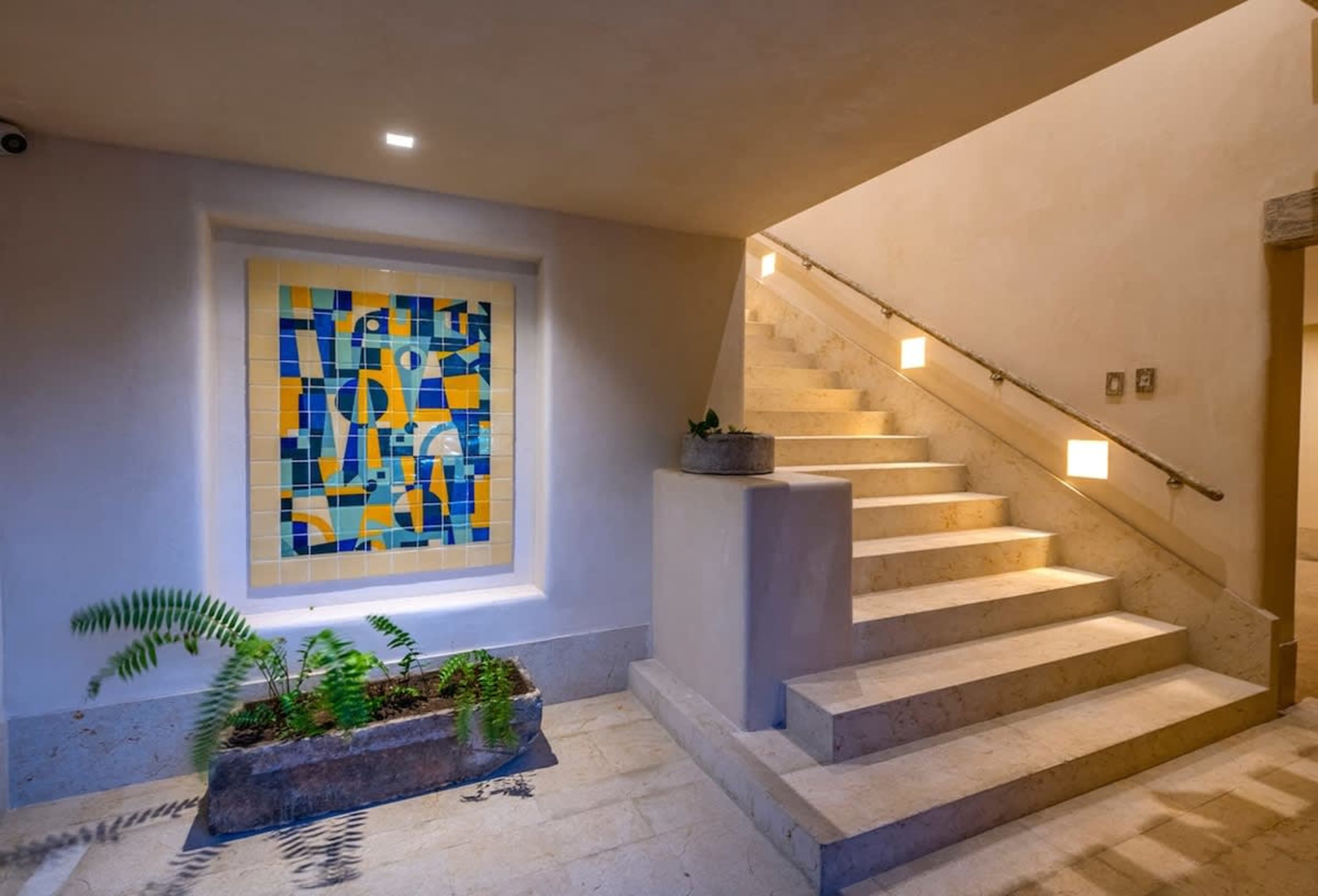 A modern staircase with artistic tile work and lush greenery.