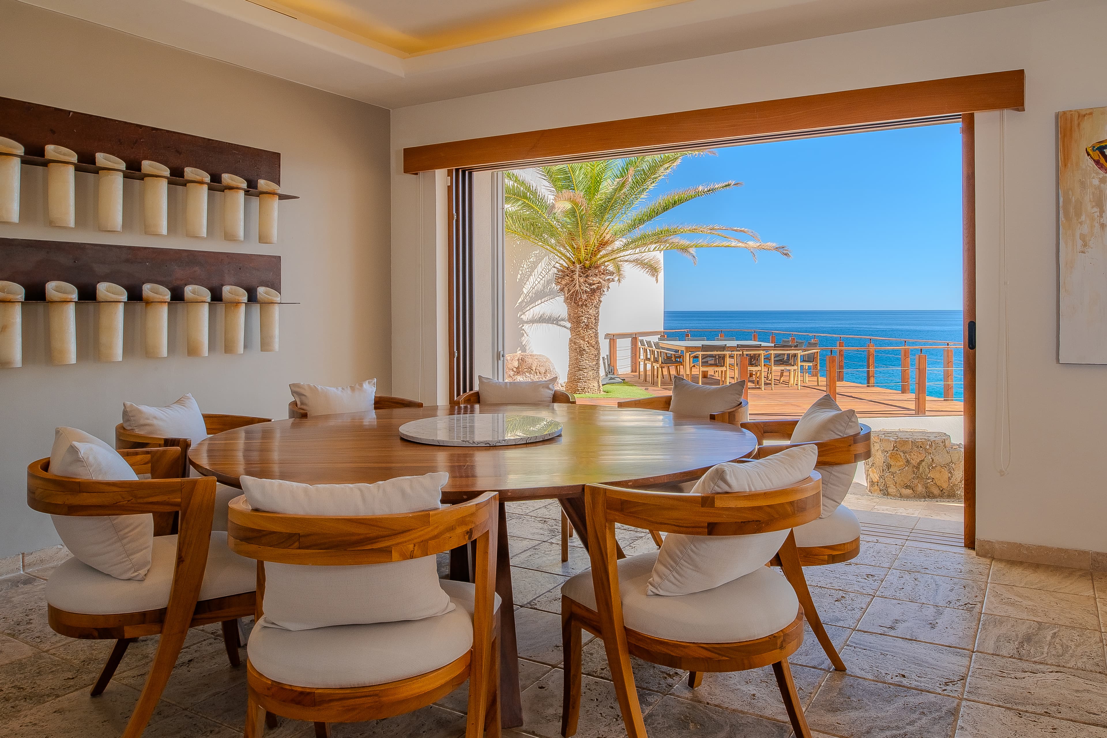 Step into your private dining space where ocean breezes and stunning sea views accompany every meal, framed by warm wood and coastal elegance.